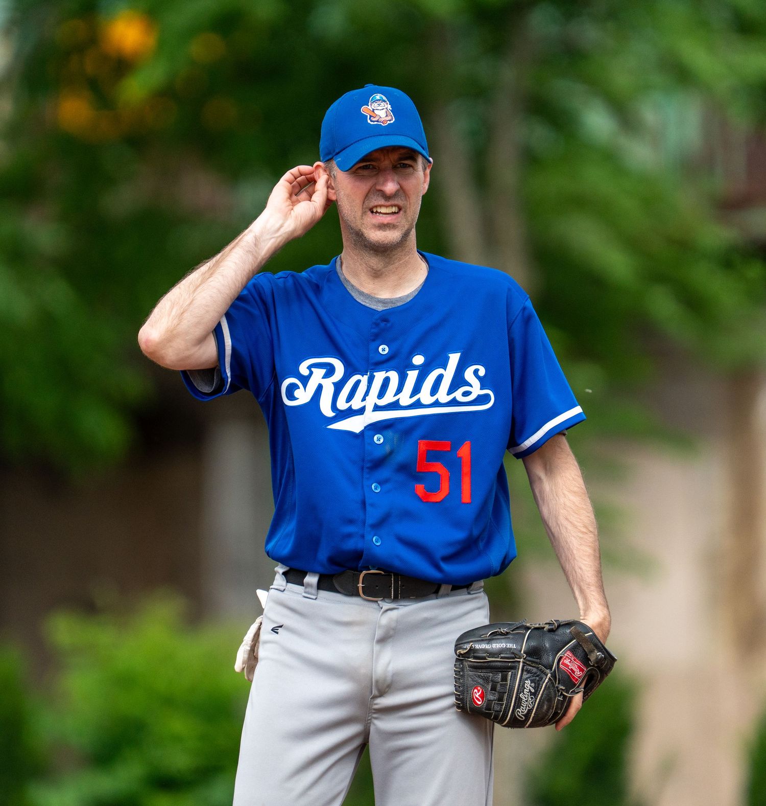 Baseball pitcher in Rapids blue jersey number 51 adjusting cap on field.