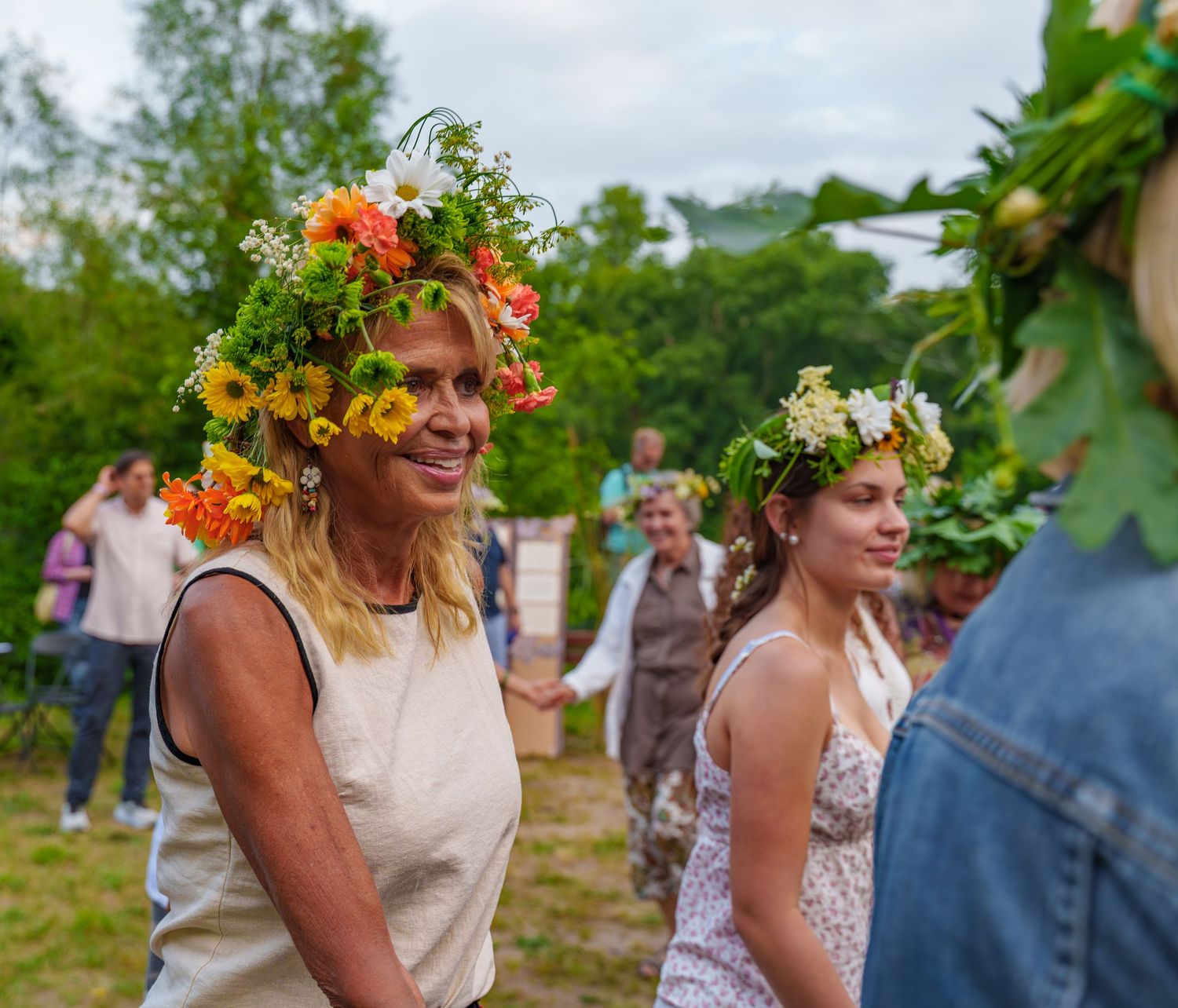 Woman wearing a colorful flower crown smiling during a traditional midsummer festival celebration.
