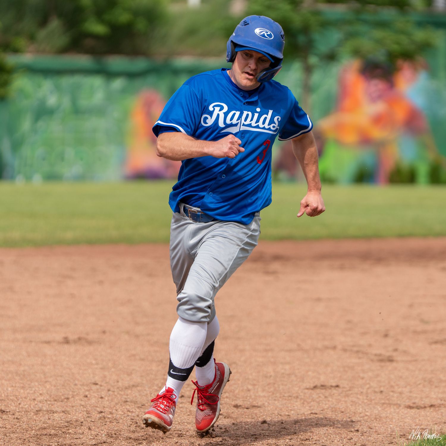 Rapids baseball player in blue uniform sprinting around the bases during a game.
