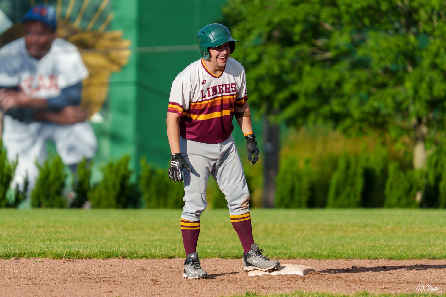 Baseball player in Miners uniform stands ready on base during a sunny outdoor game.