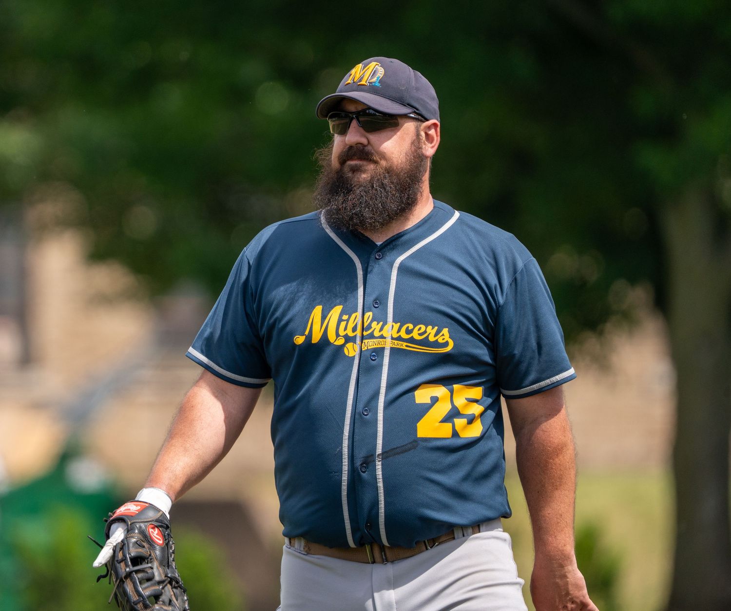 Bearded baseball player wearing Midracers number 25 navy jersey holding a glove.