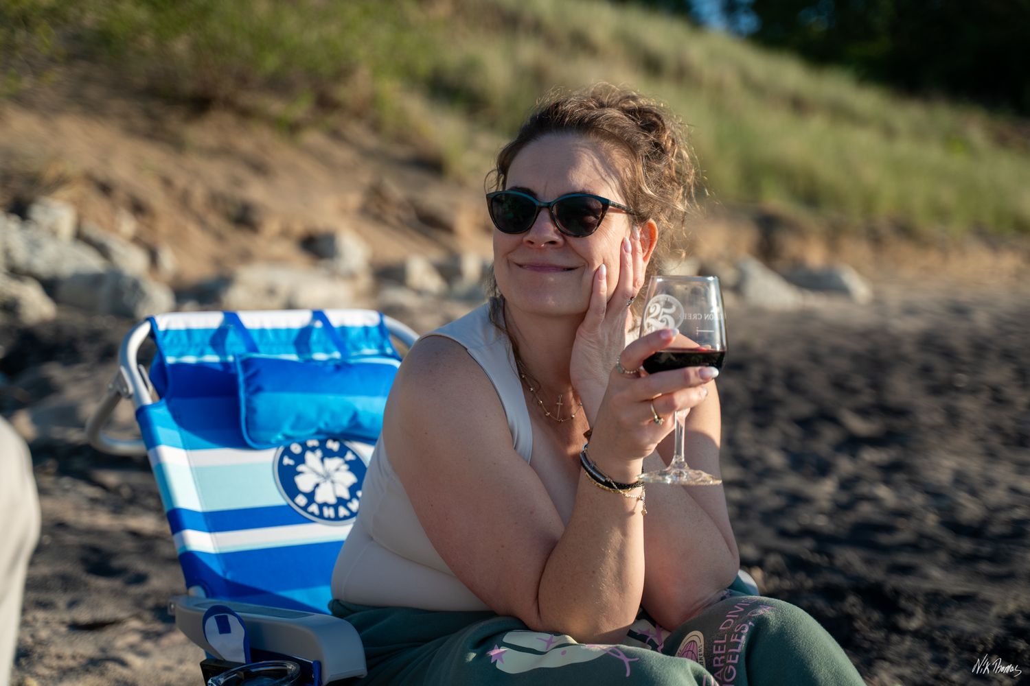lady sitting in a chair at the beach with a glass of wine