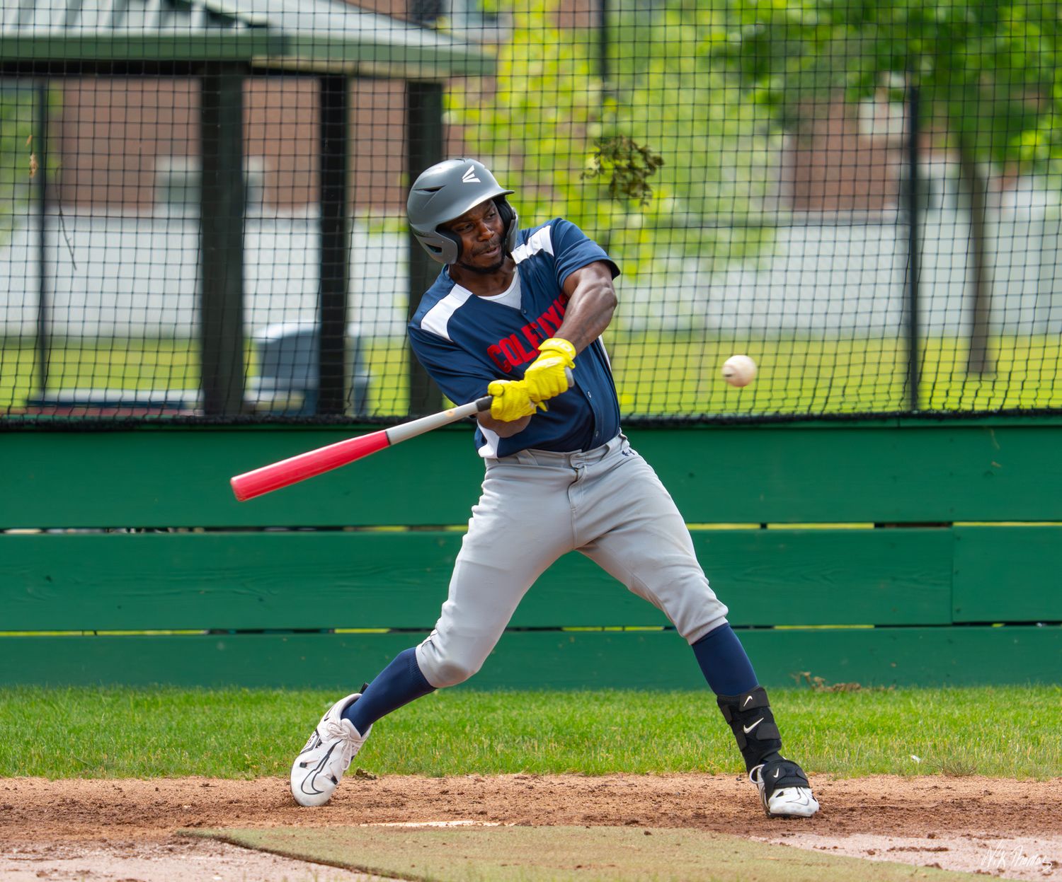 Baseball batter in gray uniform swinging at a pitch during an outdoor game.