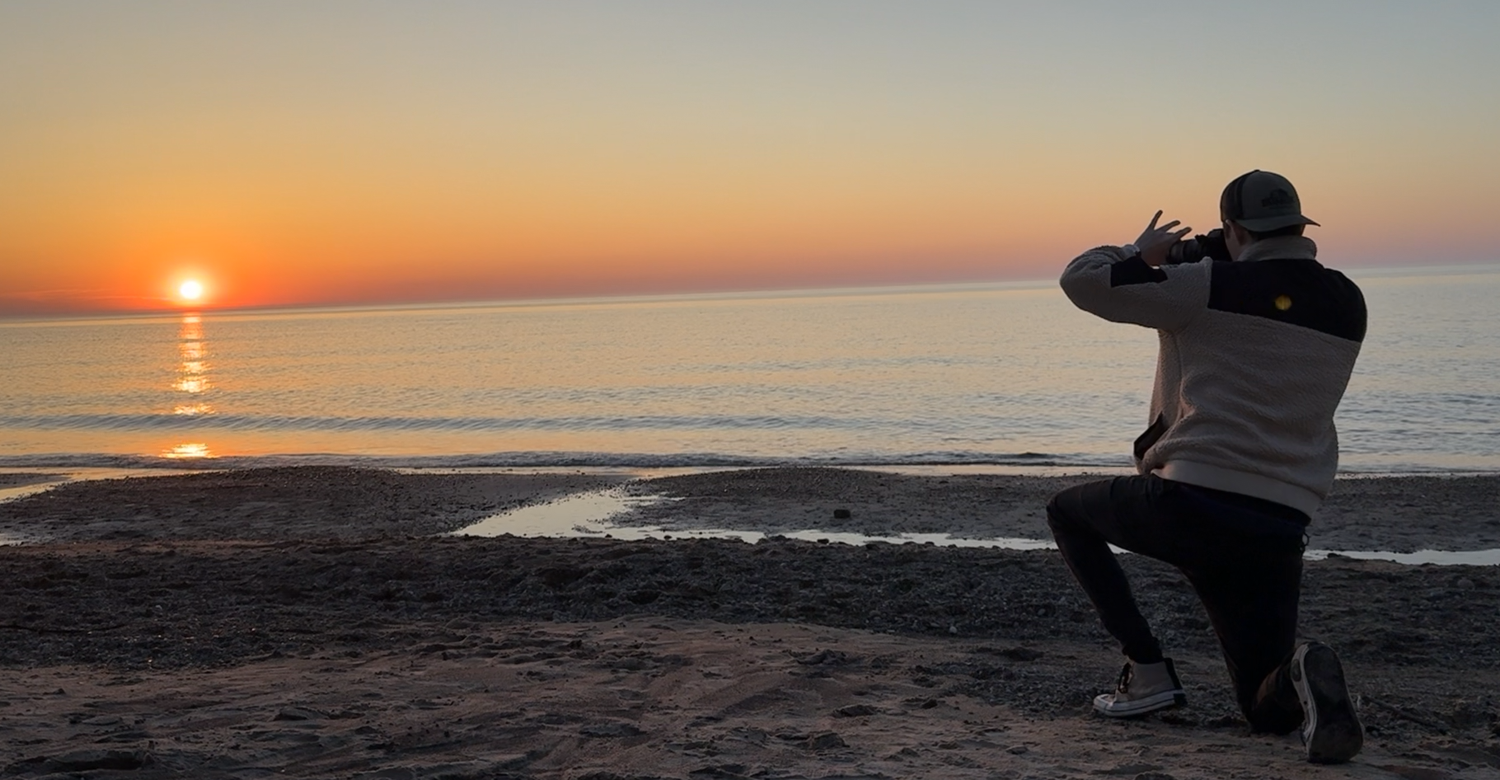 Nik Thomas taking a photo of the sunset on the beach in Beverly Shores, IN