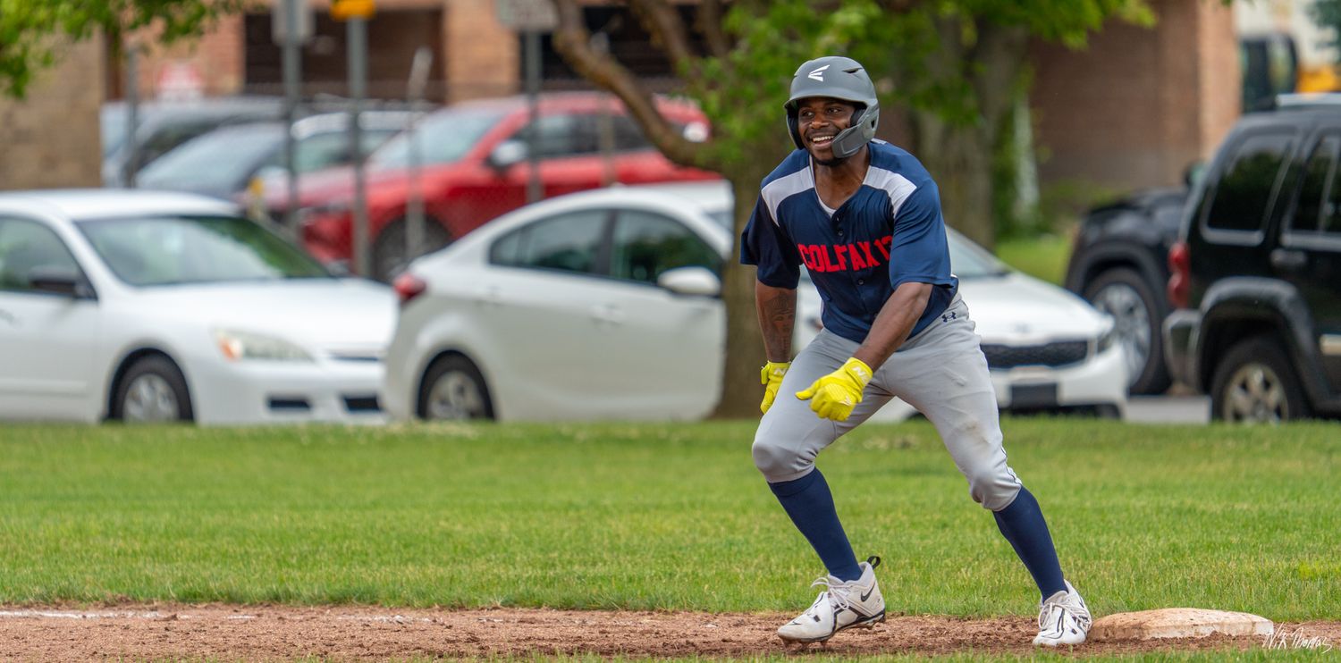 Baseball player in blue uniform taking a lead off base during an outdoor daytime game.