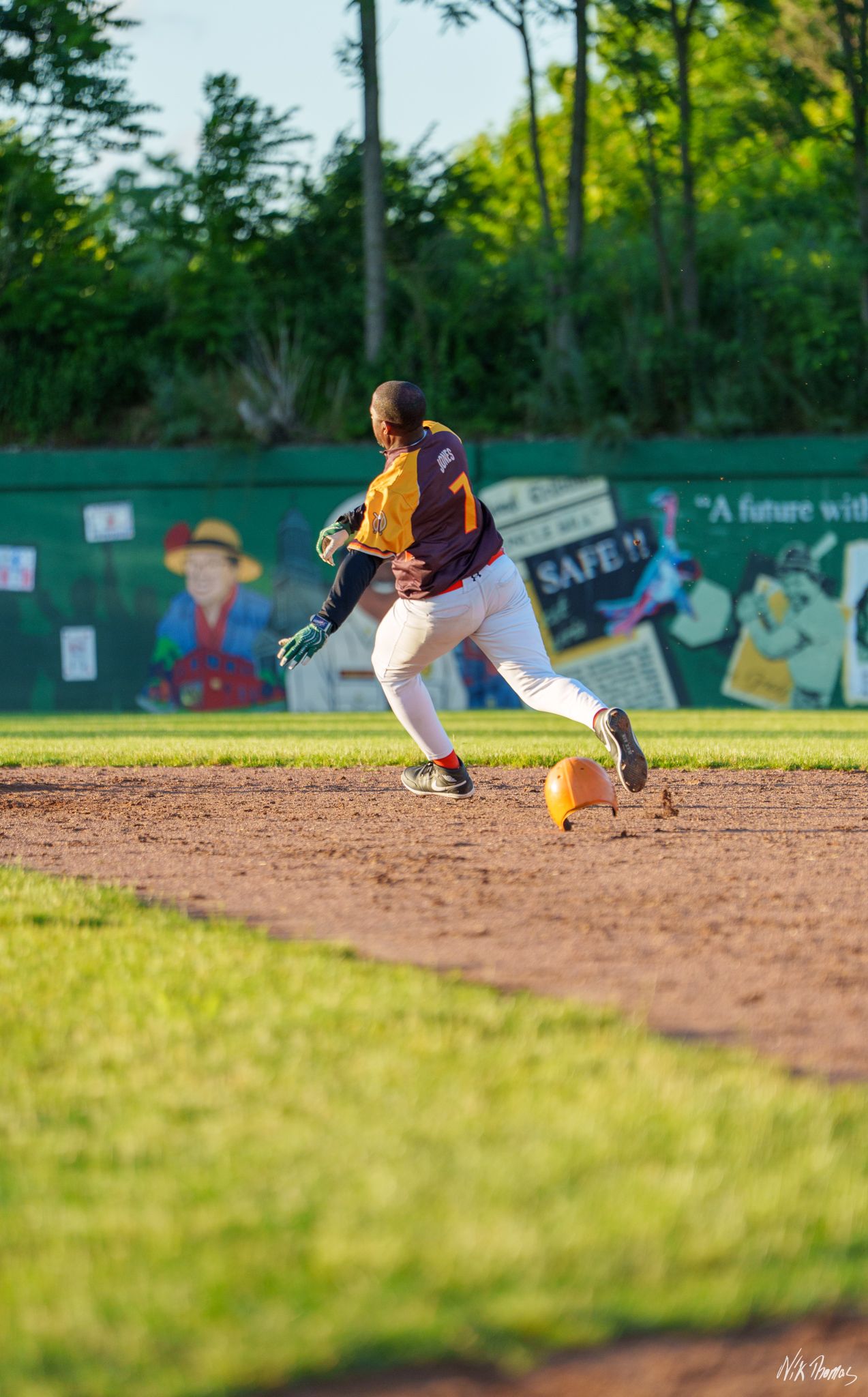 Baseball player wearing number 7 runs bases during a game on a sunny day.