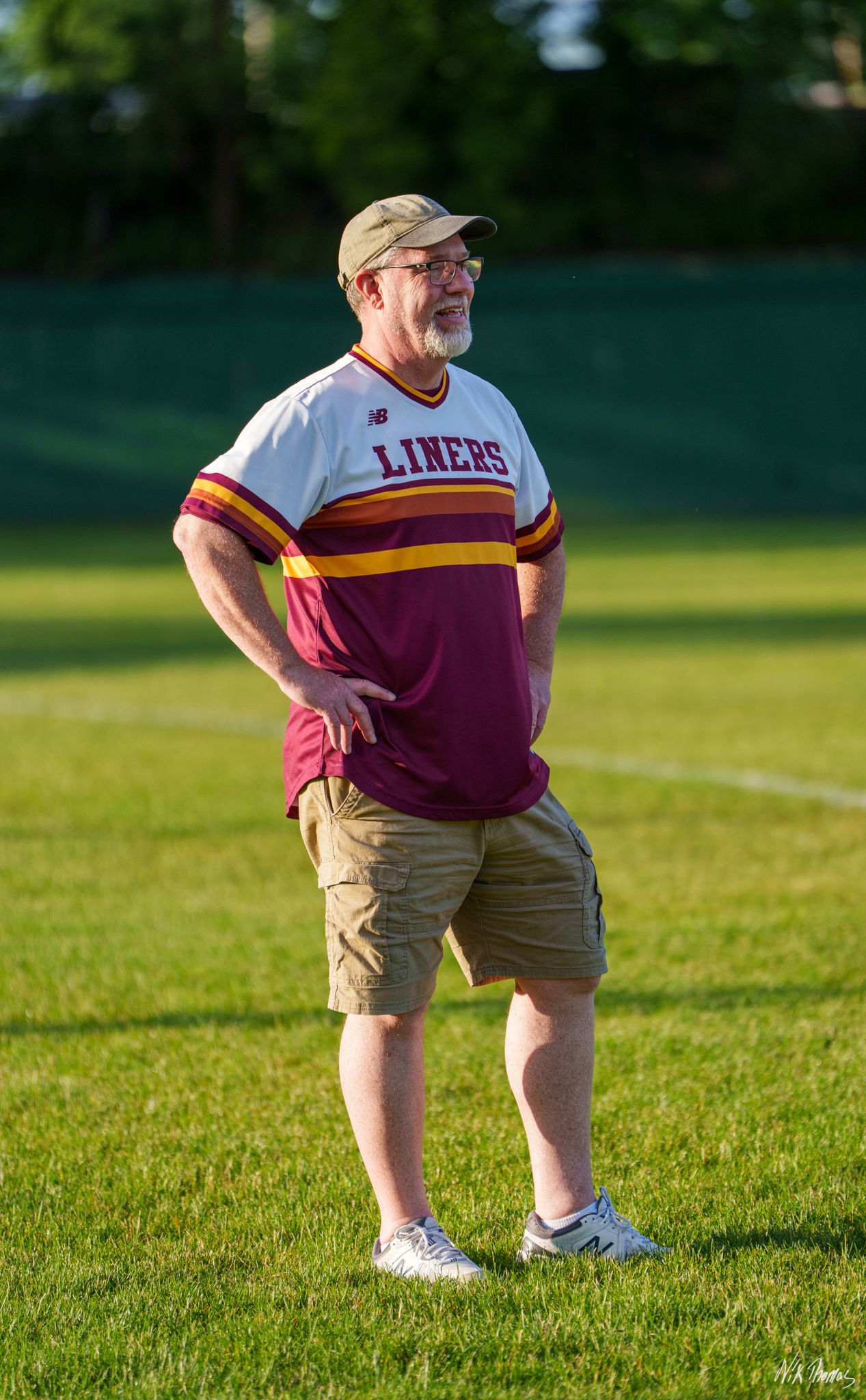 Man in Liners baseball jersey stands on green field watching game.