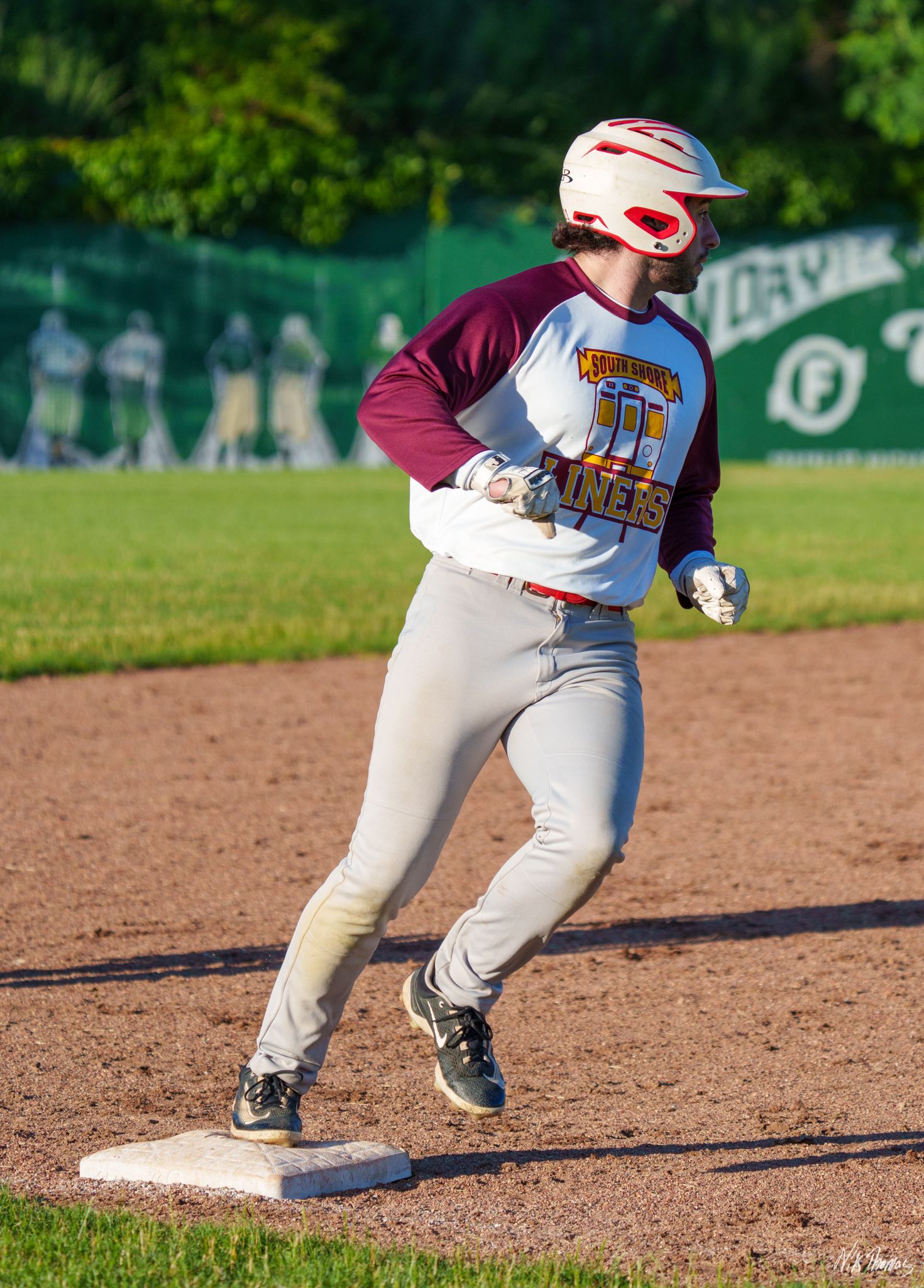 Liners baseball player rounds a base mid-stride during an evening game.