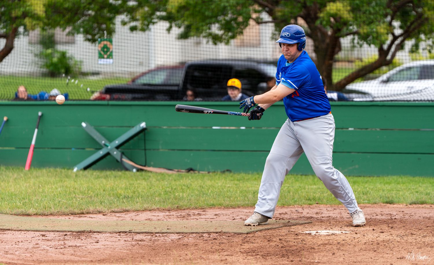 Baseball player in blue uniform swinging bat during a game on an outdoor field.