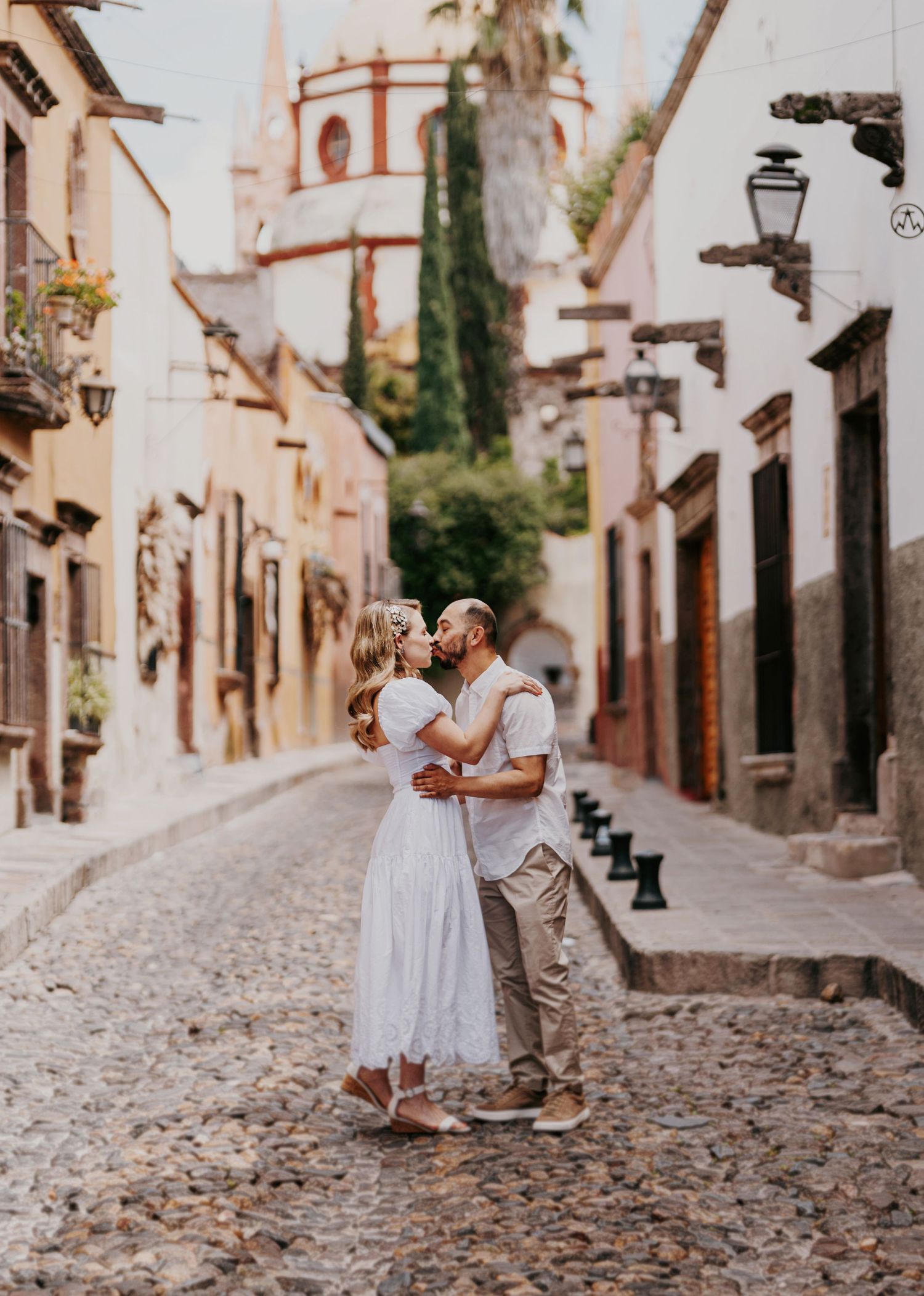 Couple sharing a romantic kiss on a charming cobblestone street in San Miguel de Allende, Mexico.