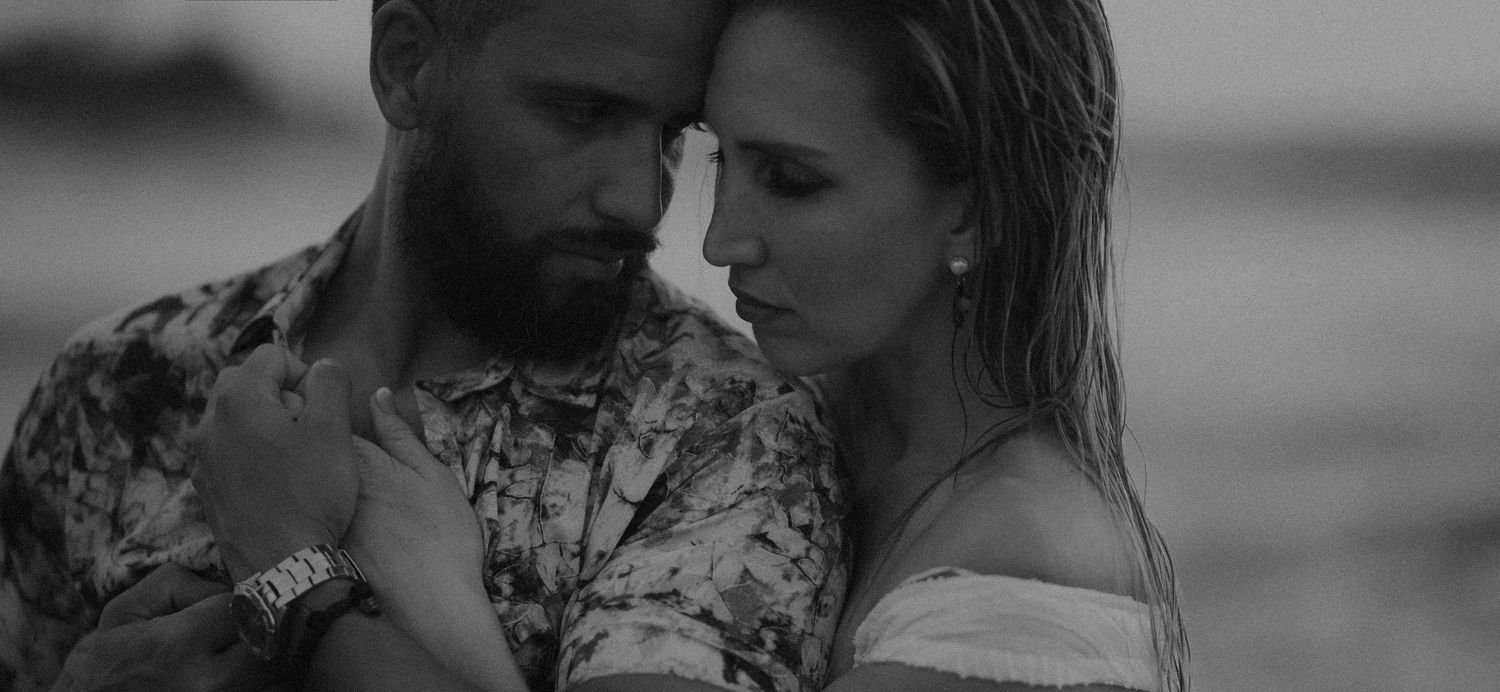Intimate black and white photo of couple embracing tenderly at the beach.