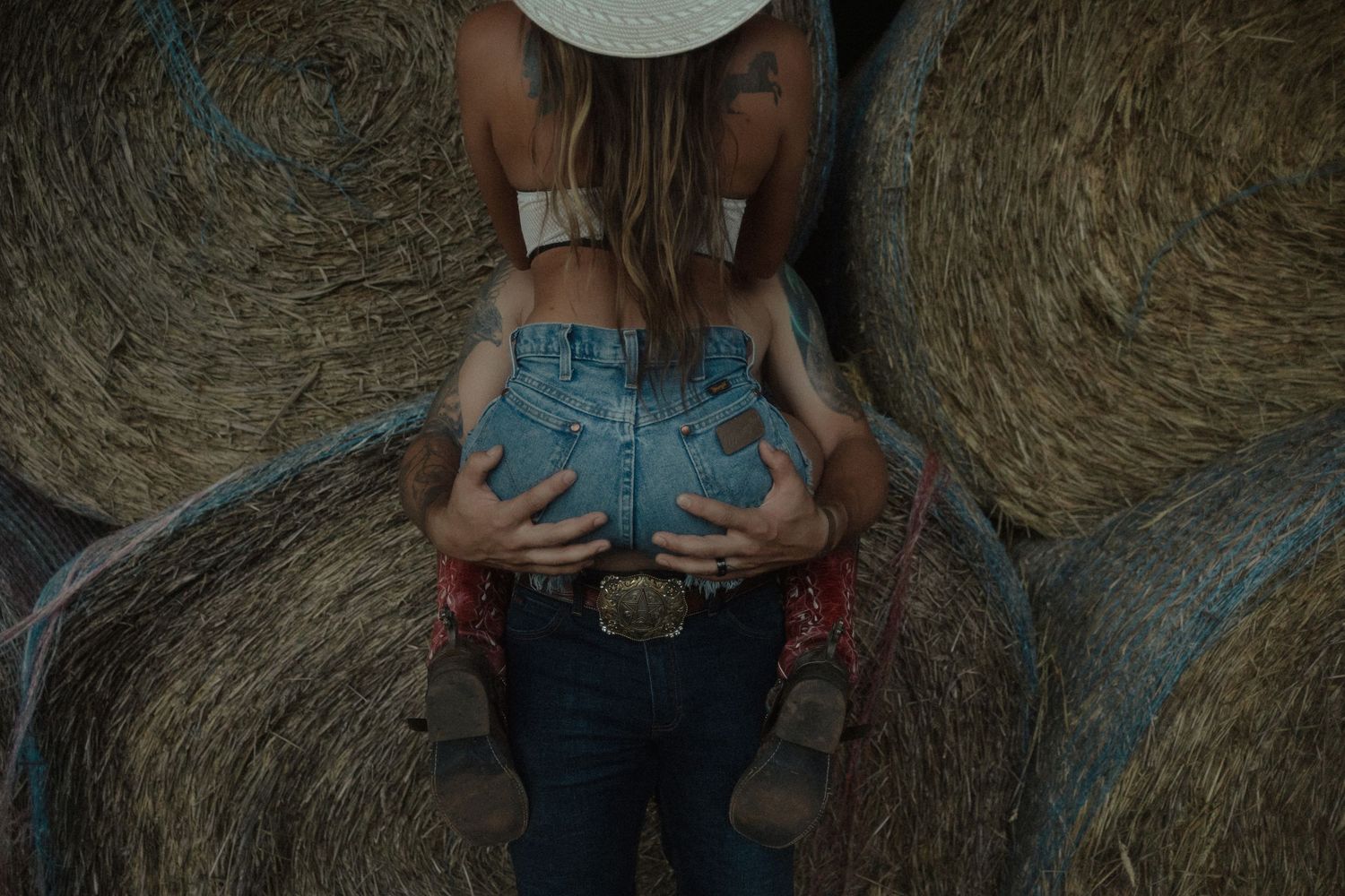 Close-up of a couple embracing near rustic hay bales on a farm.