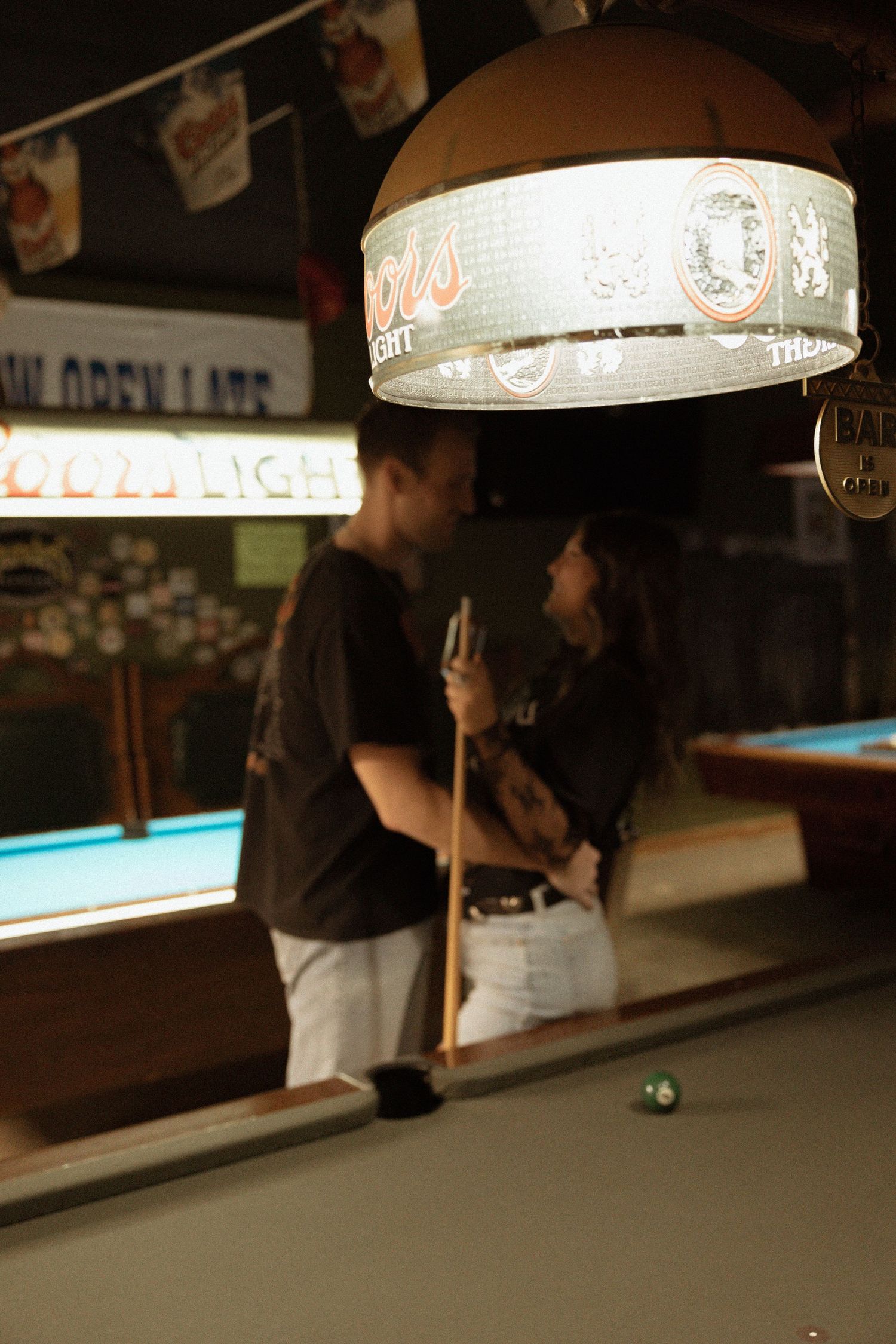 Couple sharing a tender moment near a pool table in a vintage bar.
