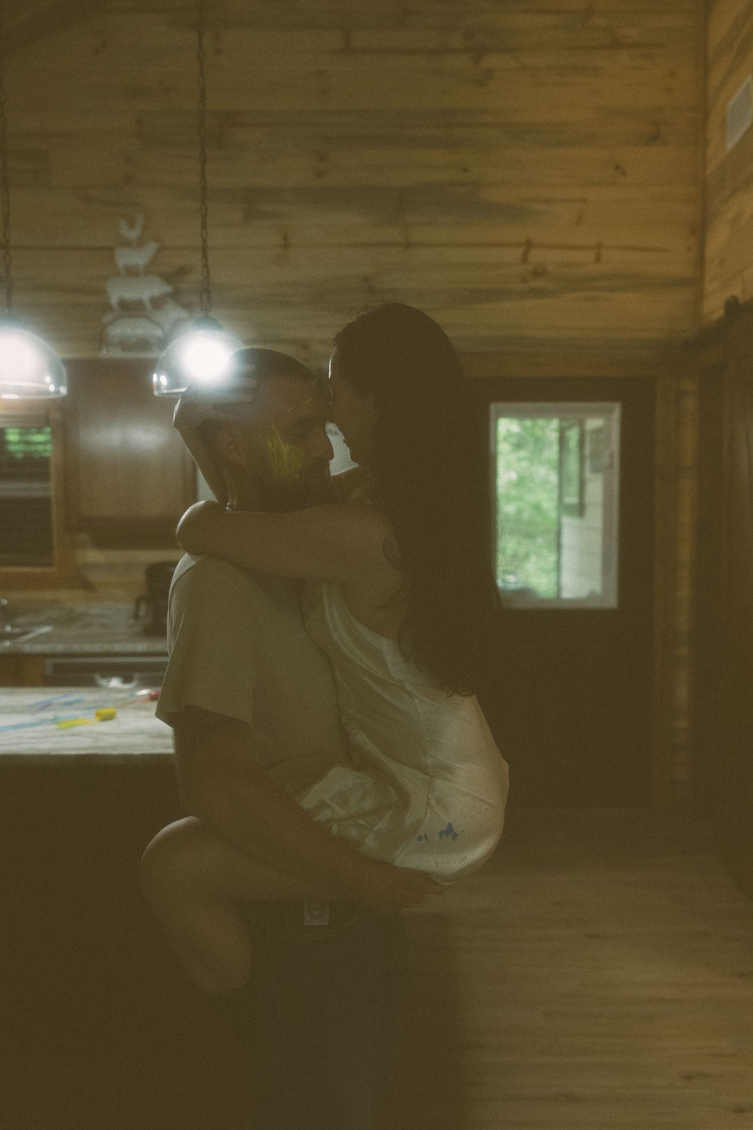 Couple sharing an intimate moment in a cozy rustic log cabin kitchen.