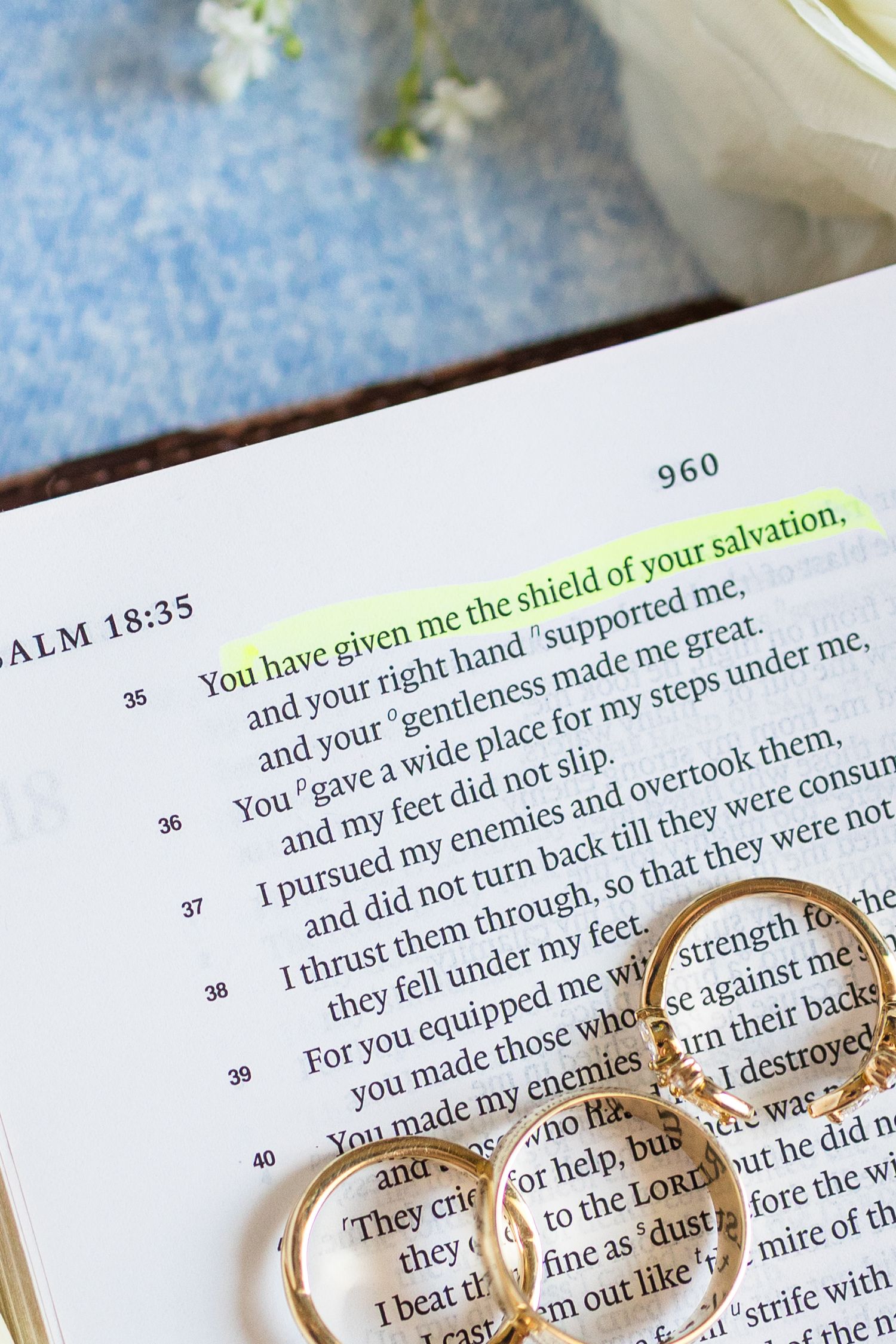 Open Bible showing Psalm 18:35 with highlighted verses and two gold wedding rings resting on the pages.