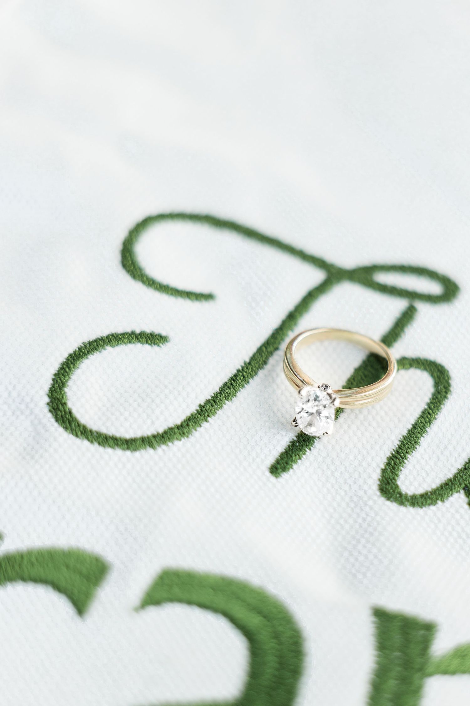 Round solitaire diamond engagement ring in gold setting resting on embroidered The Franks golf pennant flag.