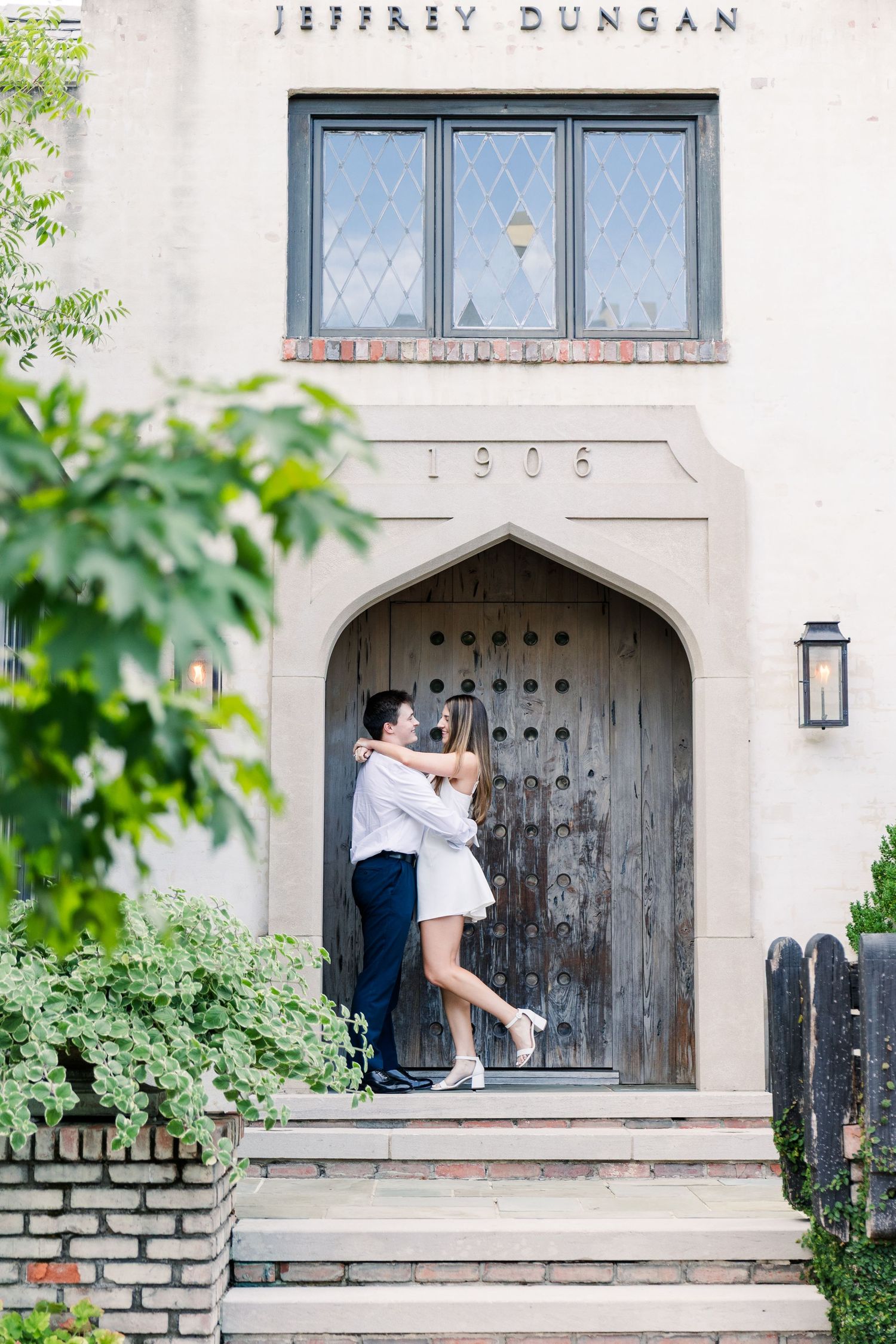 Couple embracing in front of a grand arched wooden door at the Jeffrey Dungan historic 1906 building.