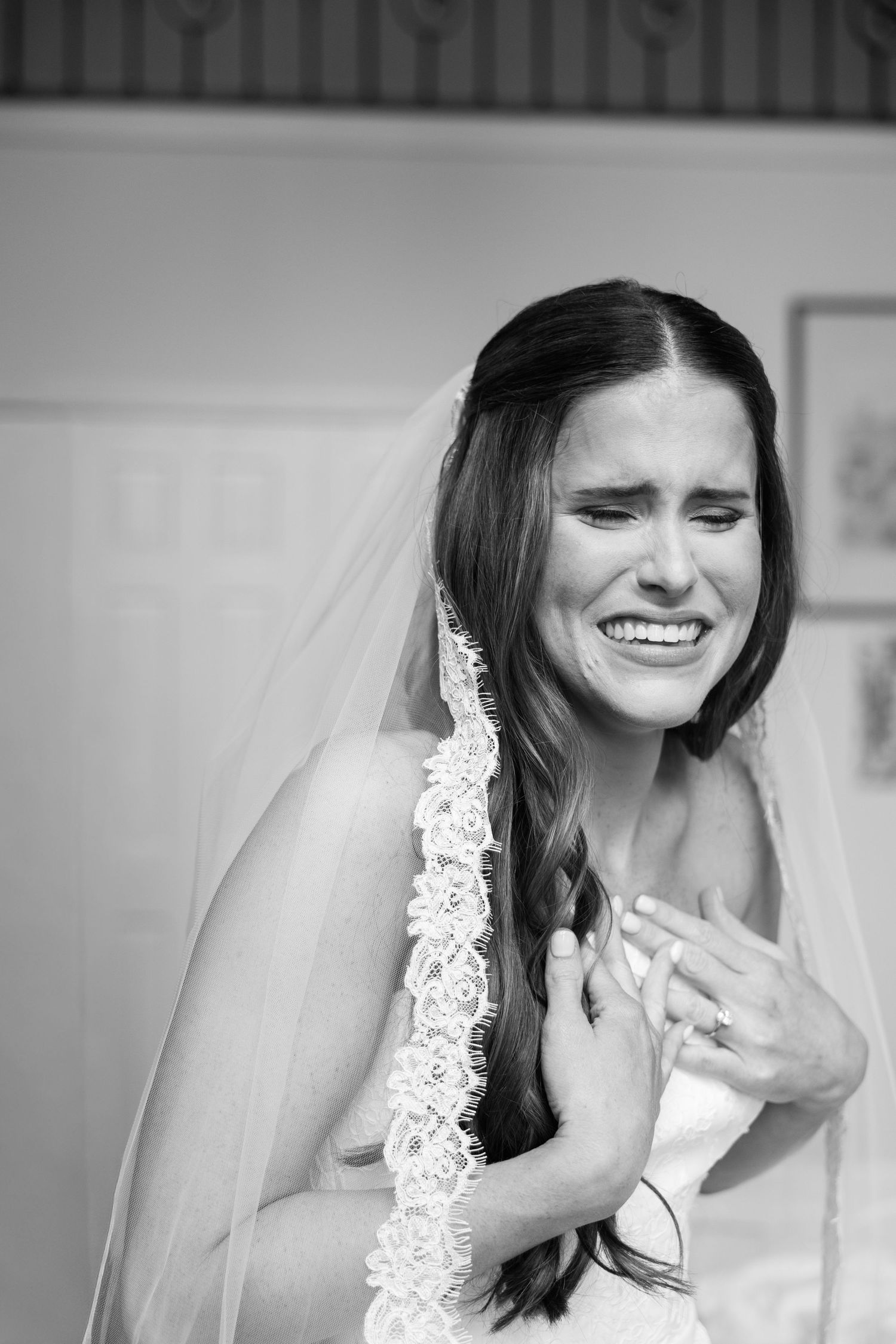 Black and white photo of an emotional bride in veil and gown, crying tears of joy on her wedding day.