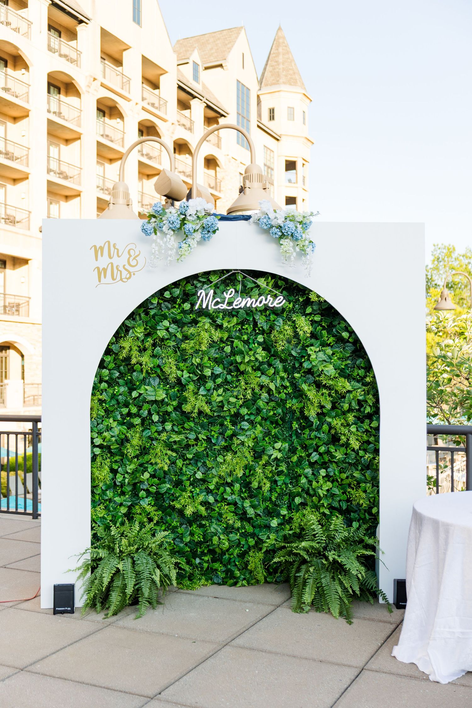 Elegant wedding photo backdrop with green living wall, arch, and McLemore Mr. & Mrs. signage at outdoor venue.