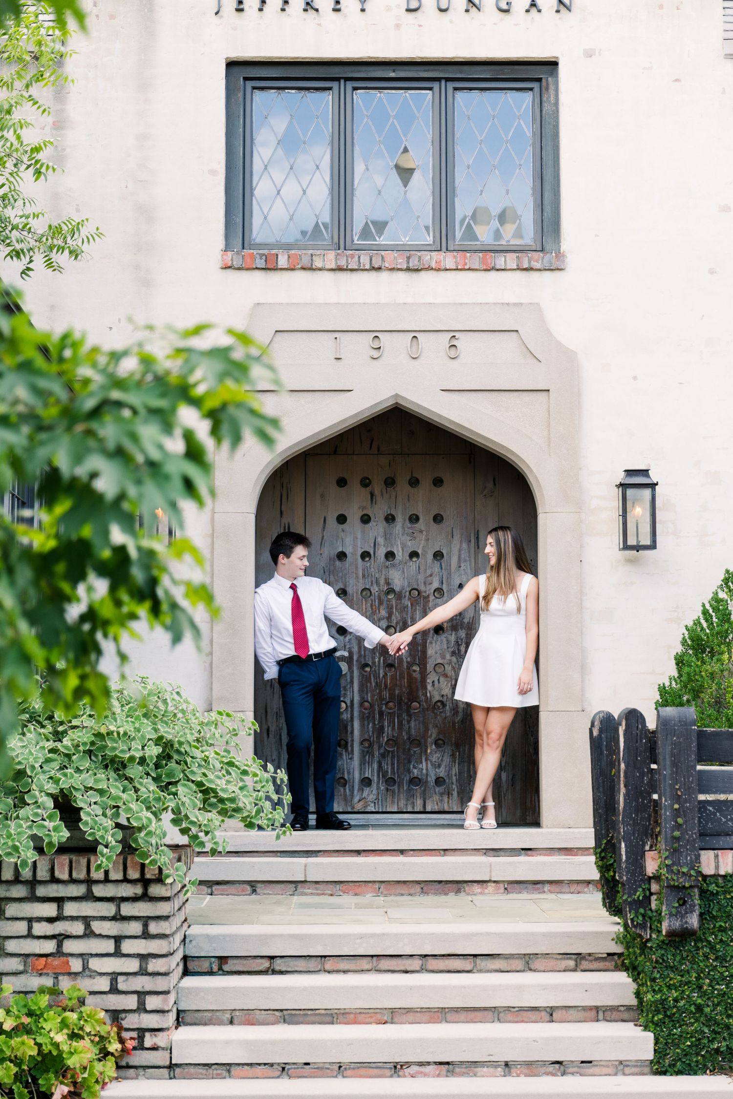 A couple holds hands in the arched entrance of the 1906 Jeffrey Dungan stone building.