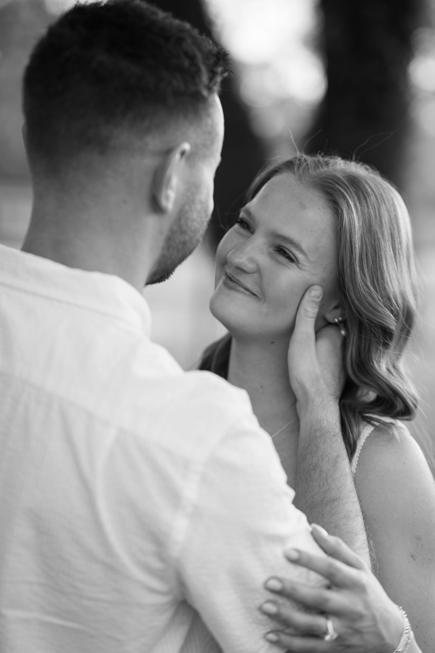 Black and white close-up of man tenderly cupping womans face during intimate engagement portrait.