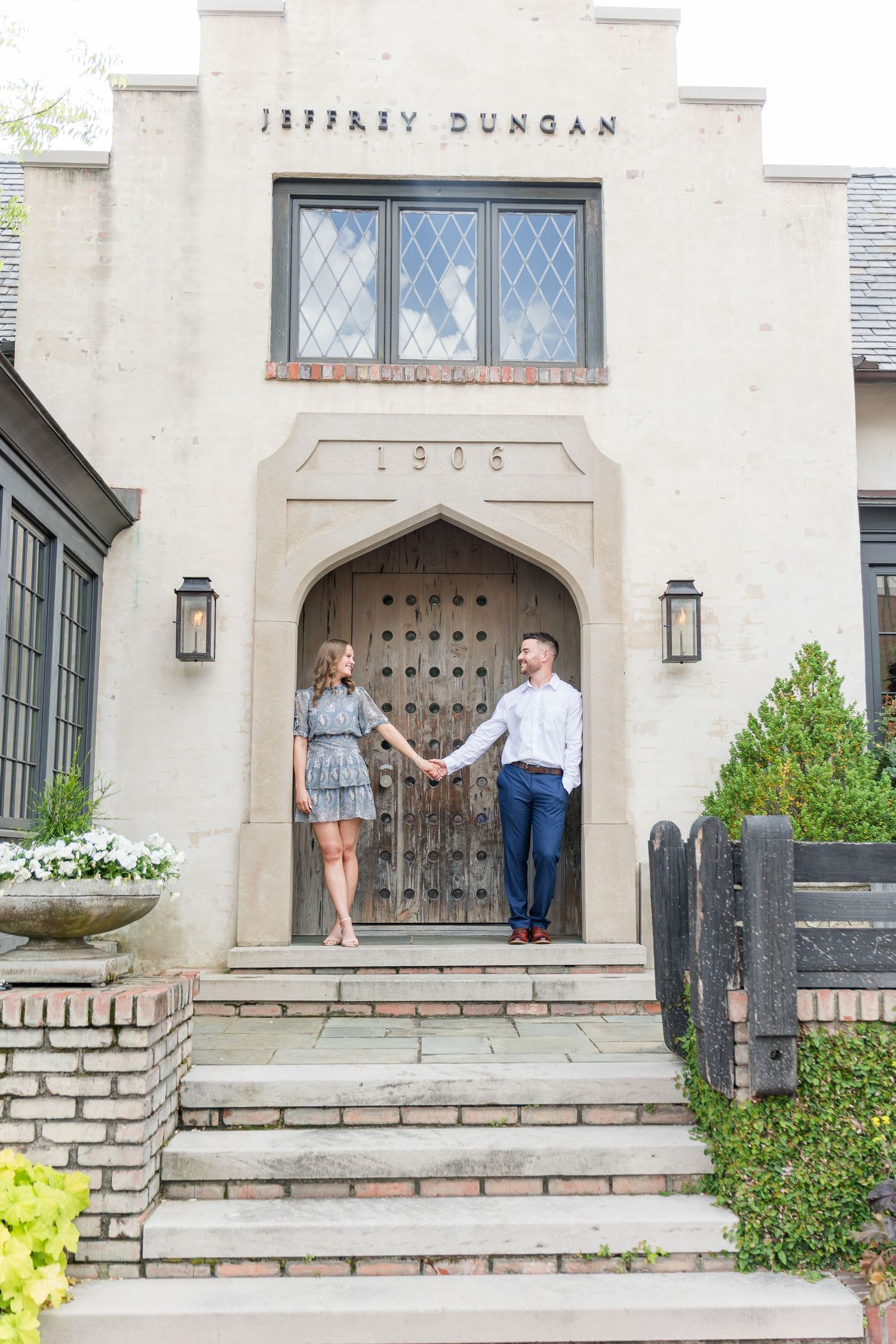 Couple holding hands on steps of Jeffrey Duncan building during an outdoor engagement session.