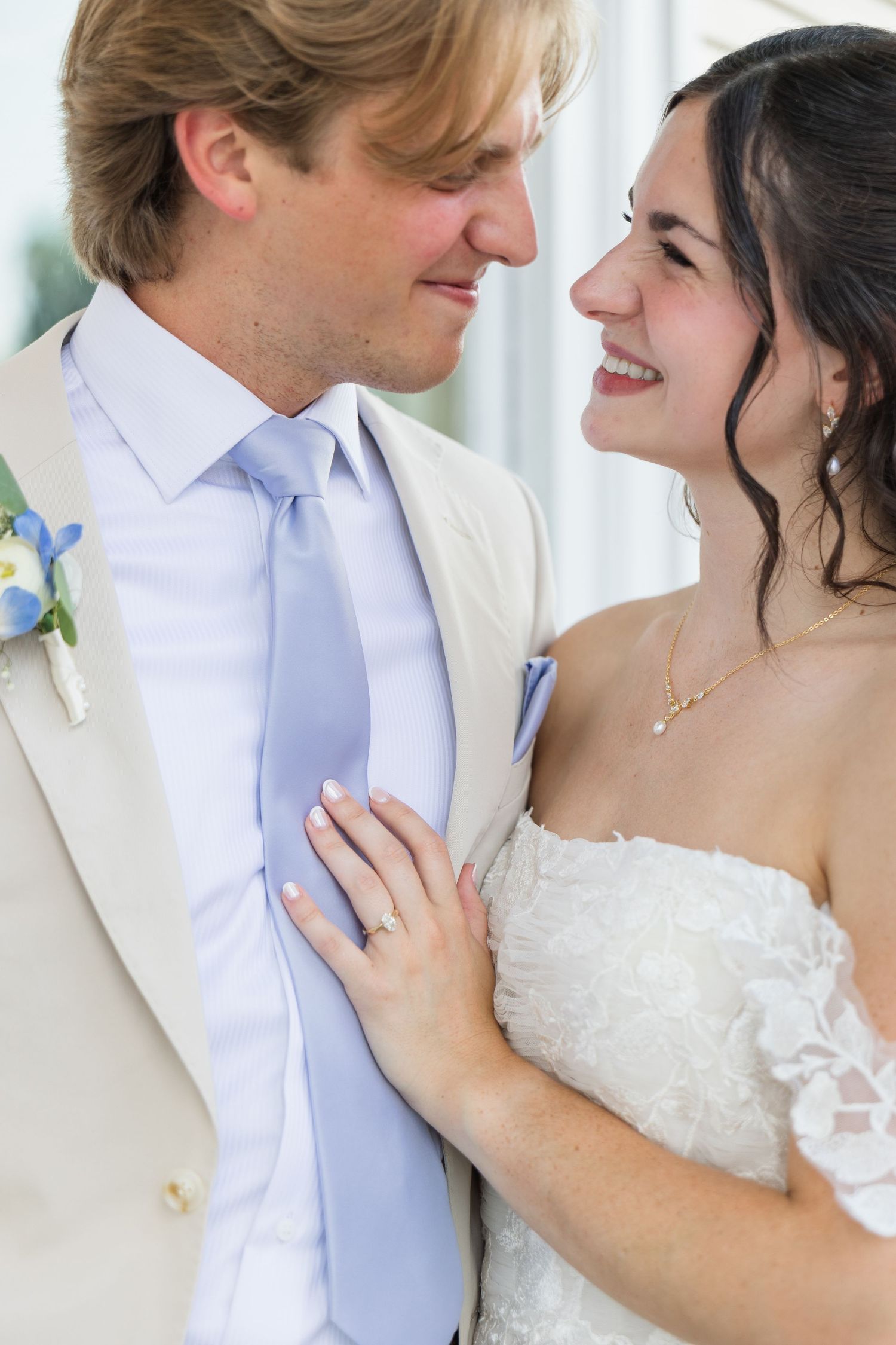 Bride and groom in tan suit sharing romantic moment gazing at each other on wedding day.