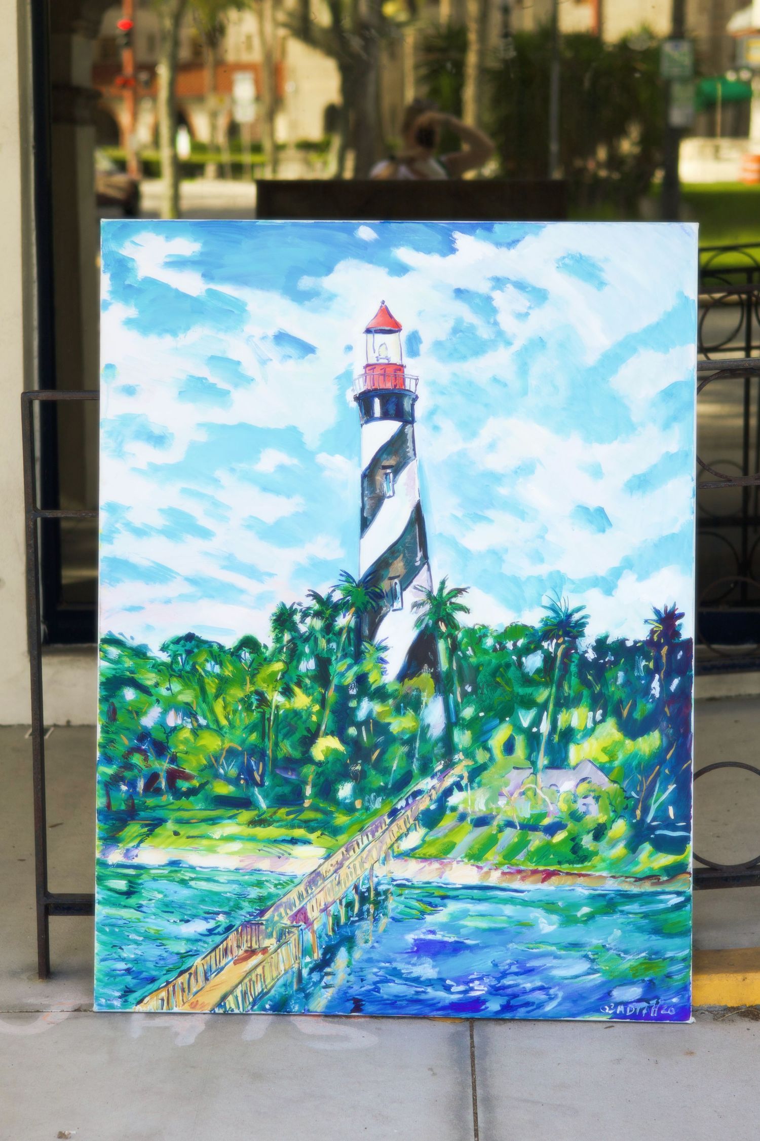 Colorful painting of St. Augustine Lighthouse with black and white stripes amid tropical palms.