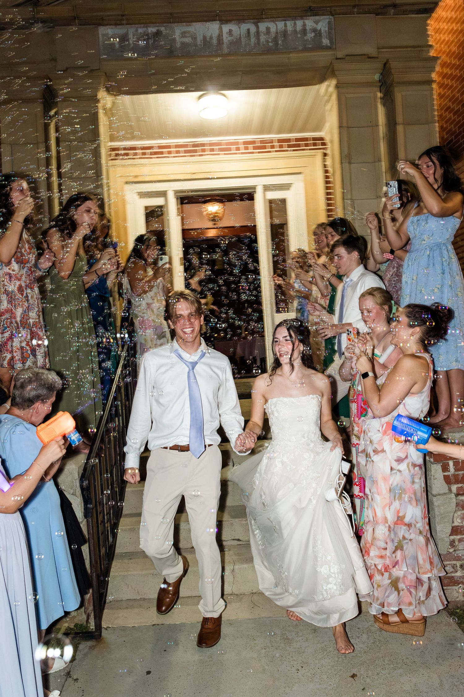 Bride and groom exit wedding venue through cheering guests blowing bubbles outside the Ice Emporium.