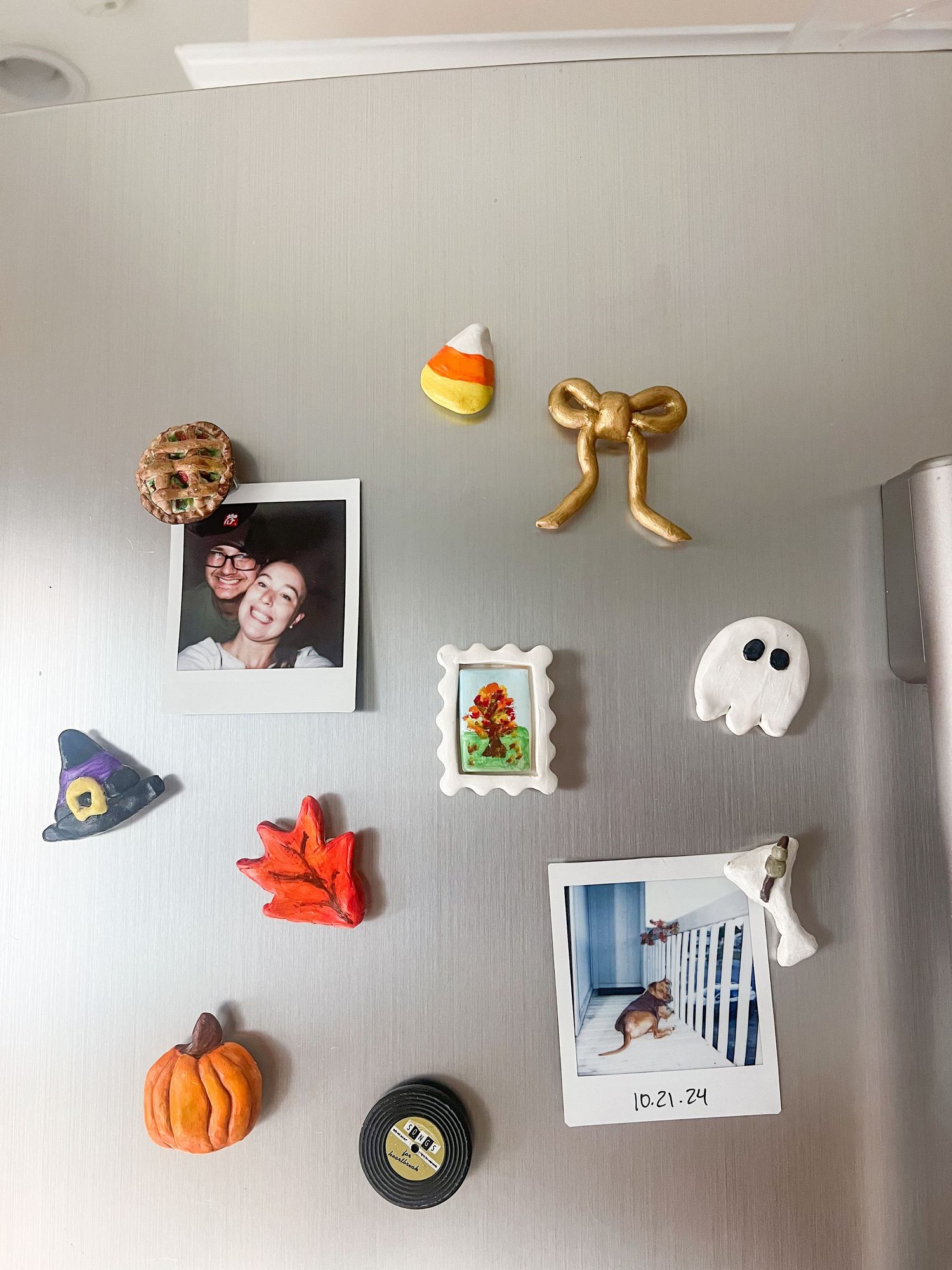 Halloween-themed refrigerator magnets including a ghost, pumpkin, witch hat, and candy corn with Polaroid photos.