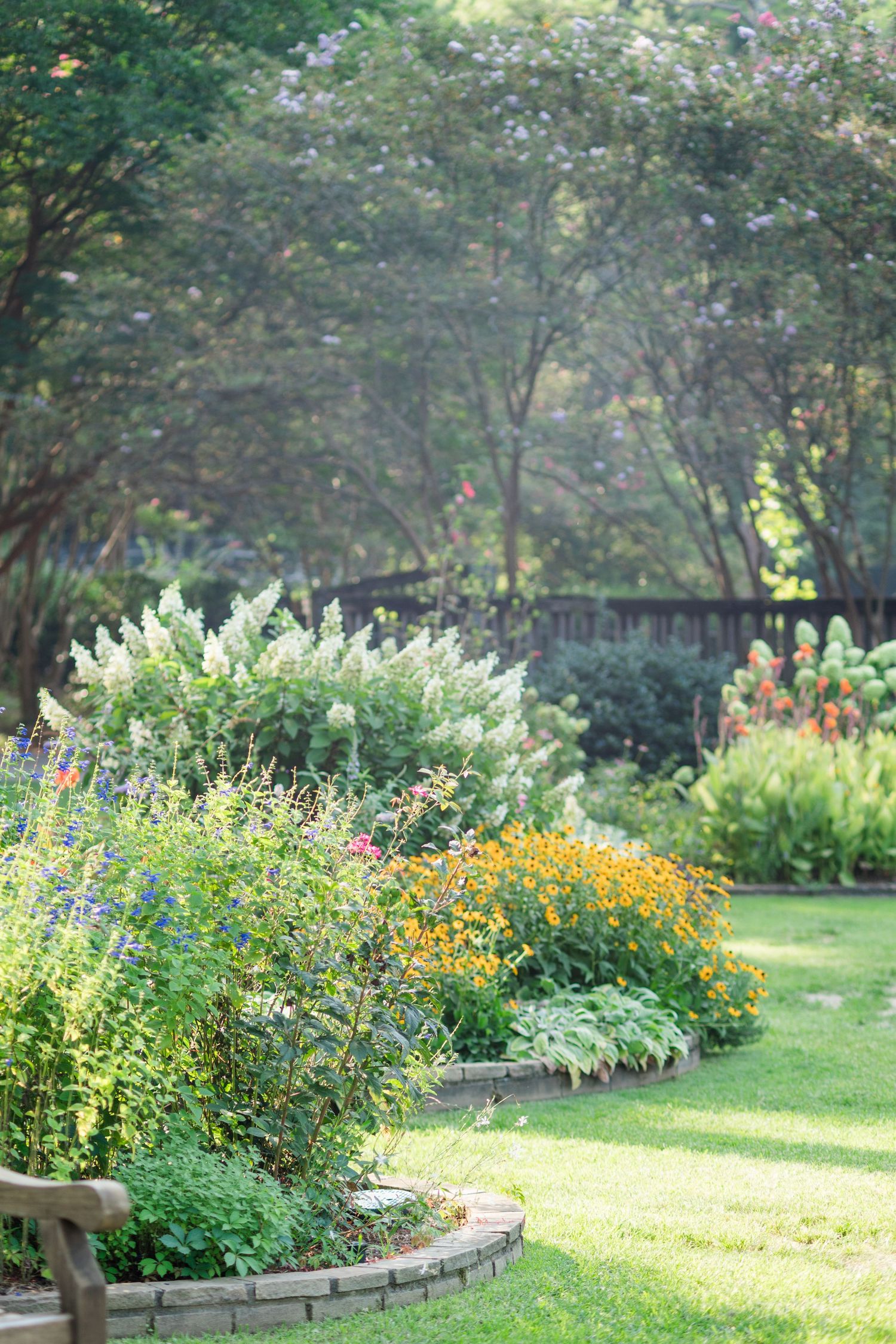 A beautifully landscaped garden featuring colorful flower borders with yellow, white, and red blooms.