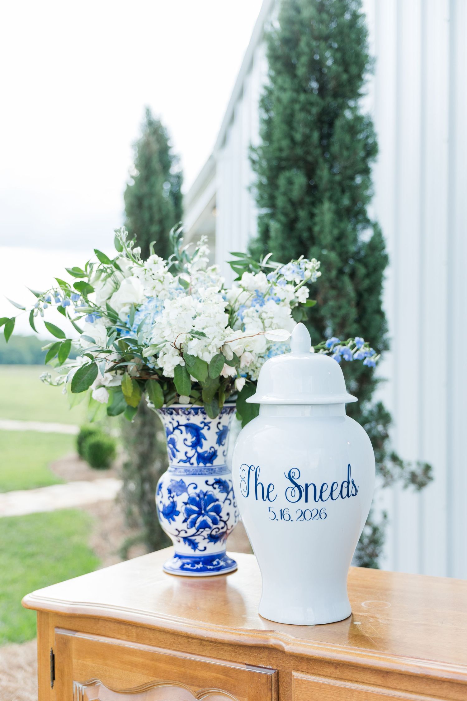 Blue and white chinoiserie vases with white and blue floral arrangements labeled The Sneeds 5.16.2026.