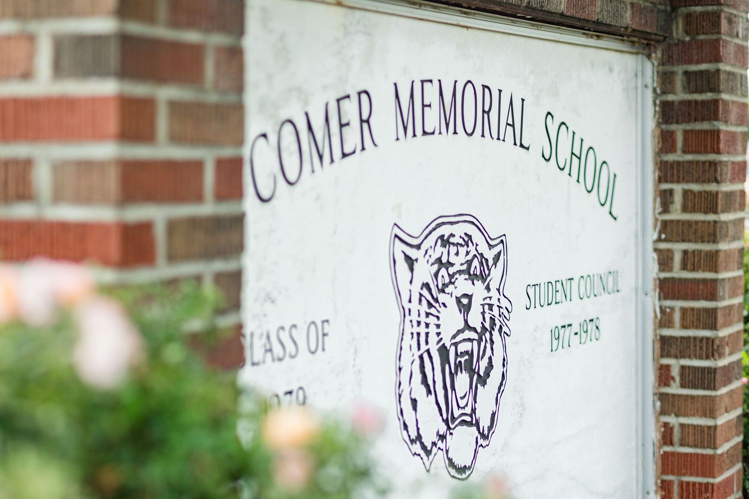 Comer Memorial School sign with tiger mascot and Student Council 1977-1979 plaque on brick wall.
