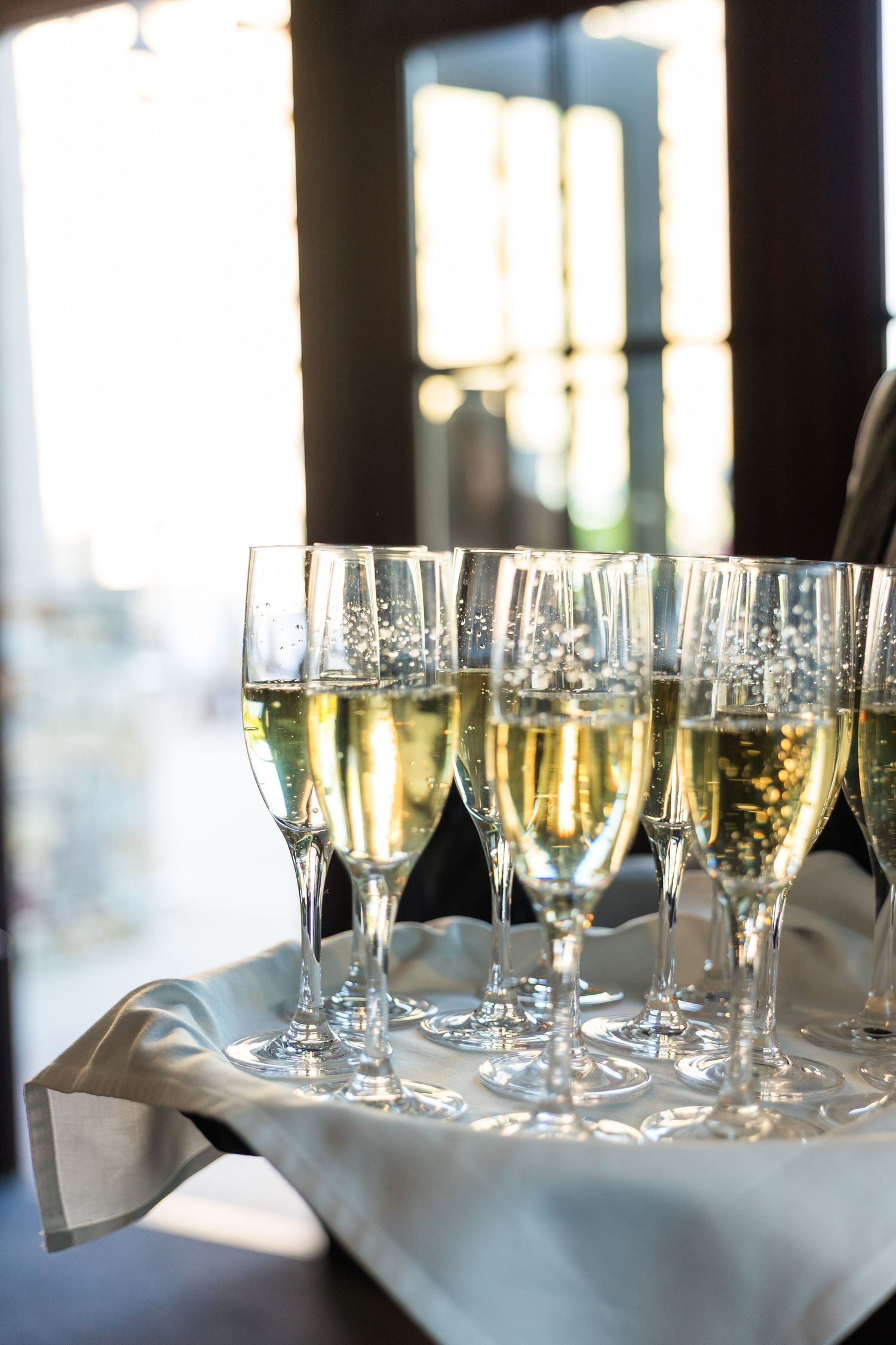 Elegant champagne flutes filled with sparkling wine arranged on a silver tray at a formal event.