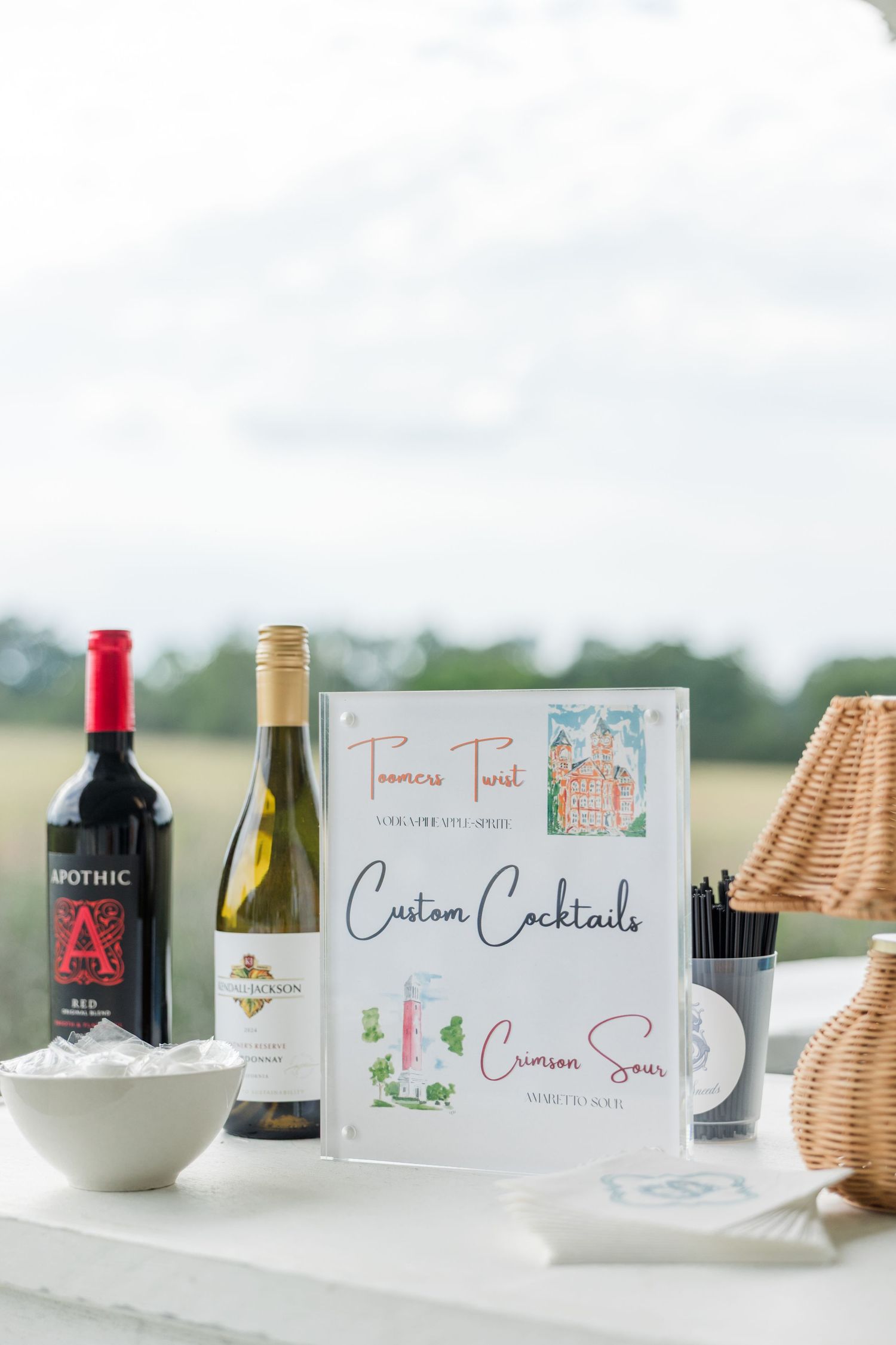 Wedding custom cocktails menu sign displayed with wine bottles, Apothic red and white wine on a white table.