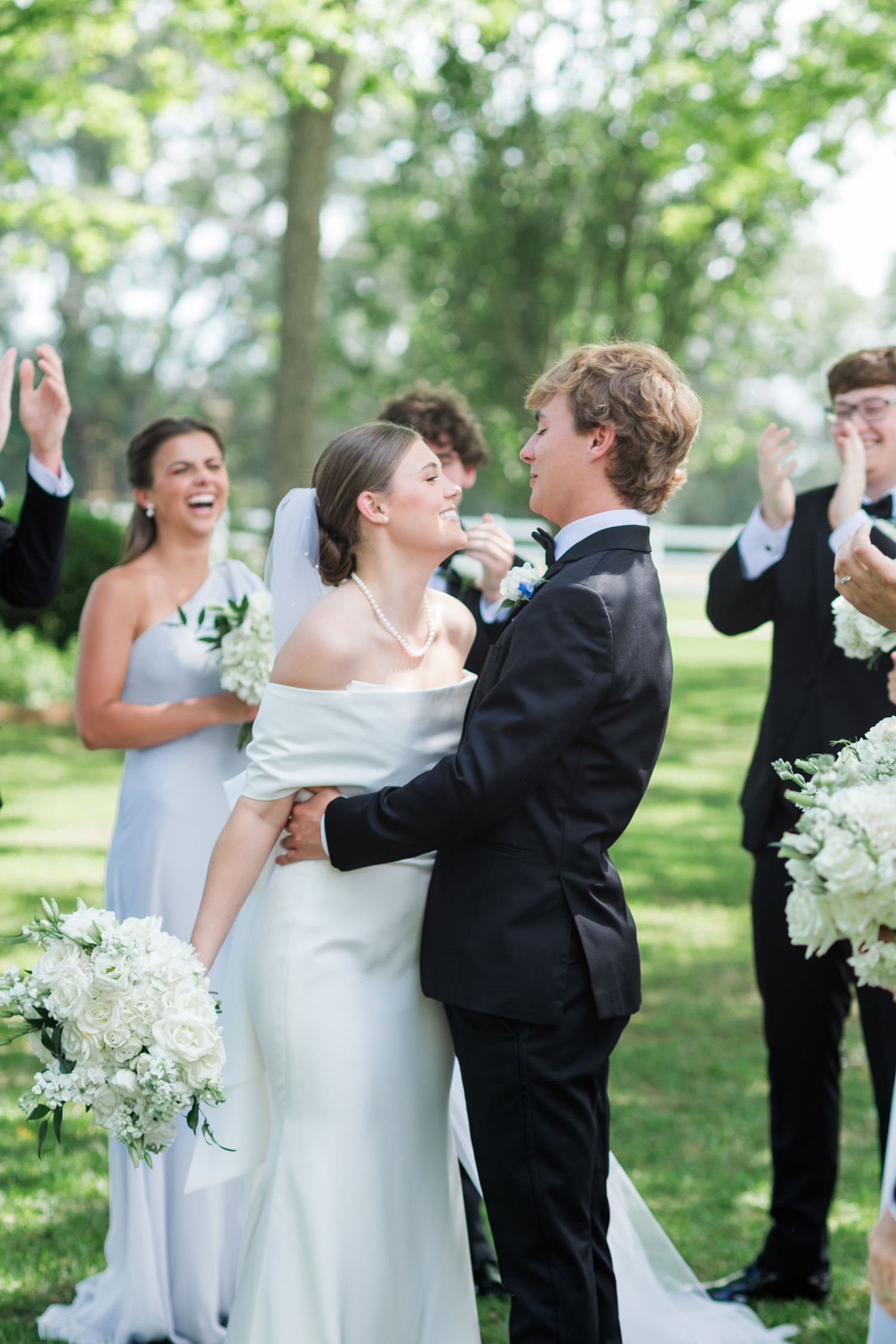 A bride and groom share a joyful moment during their outdoor wedding ceremony surrounded by cheering guests.