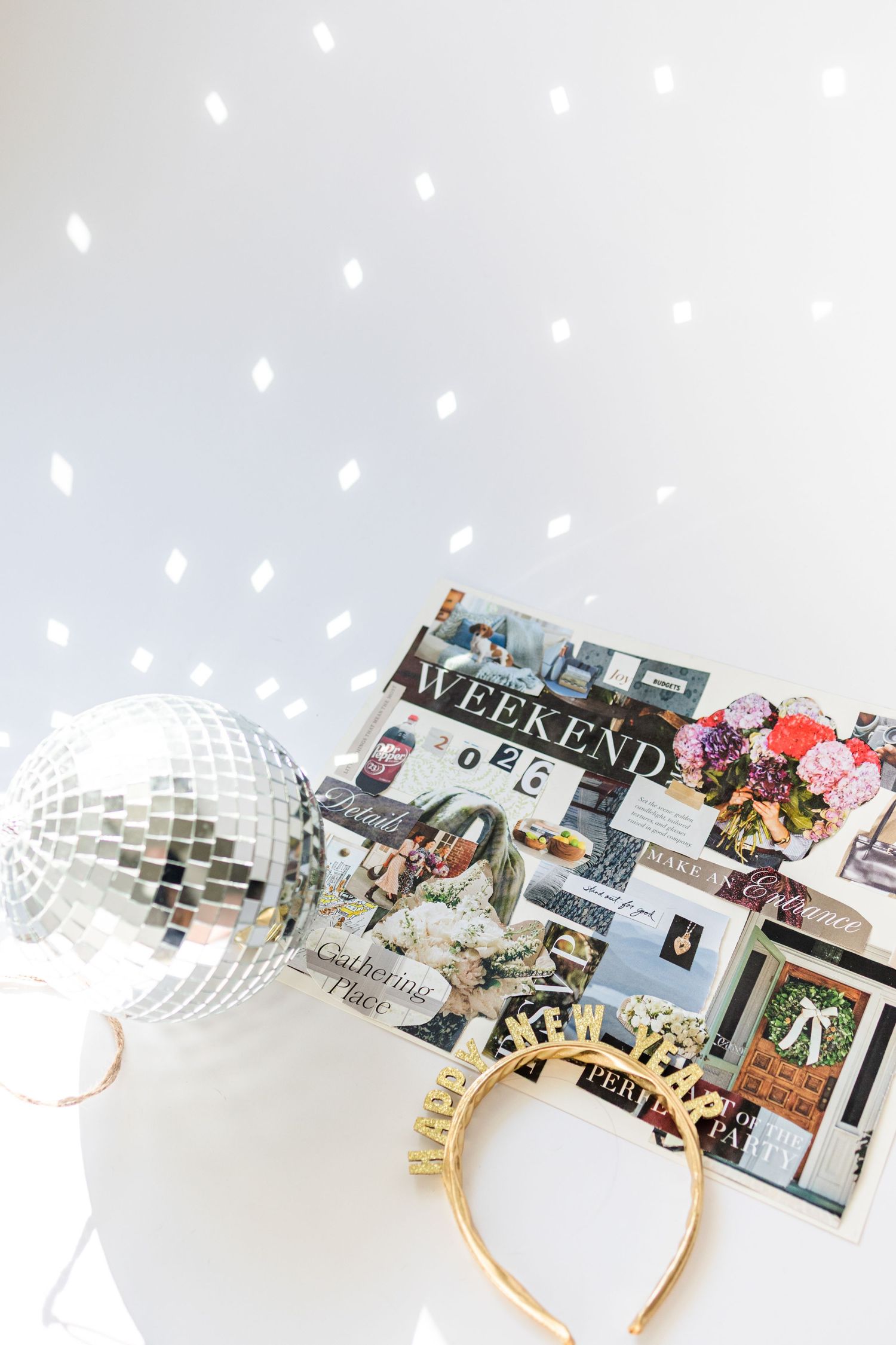 Disco ball, New Year headband, and Weekend magazine on white surface with sparkling light reflections.