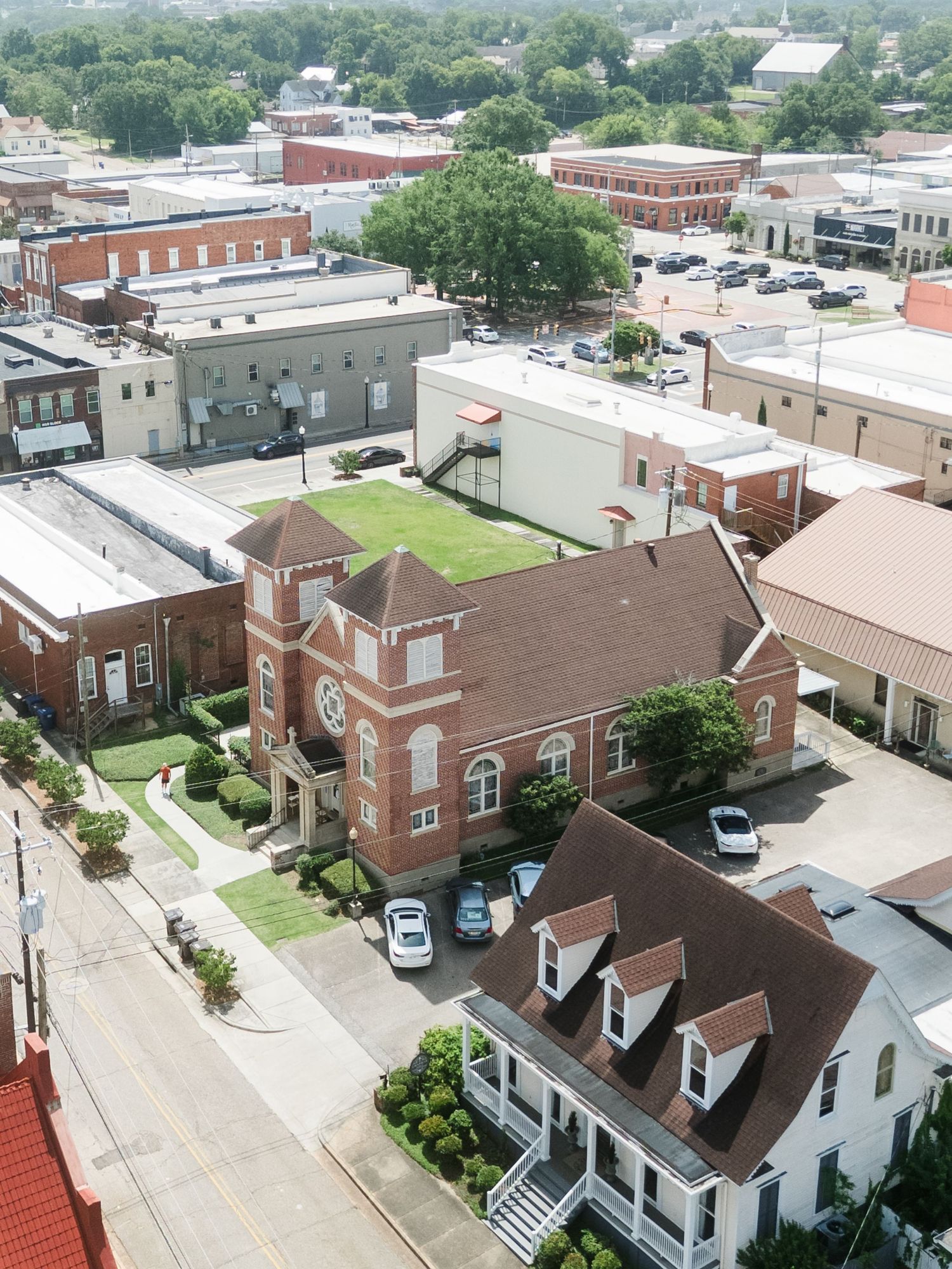 Aerial view of a historic red brick church in a small town downtown district.
