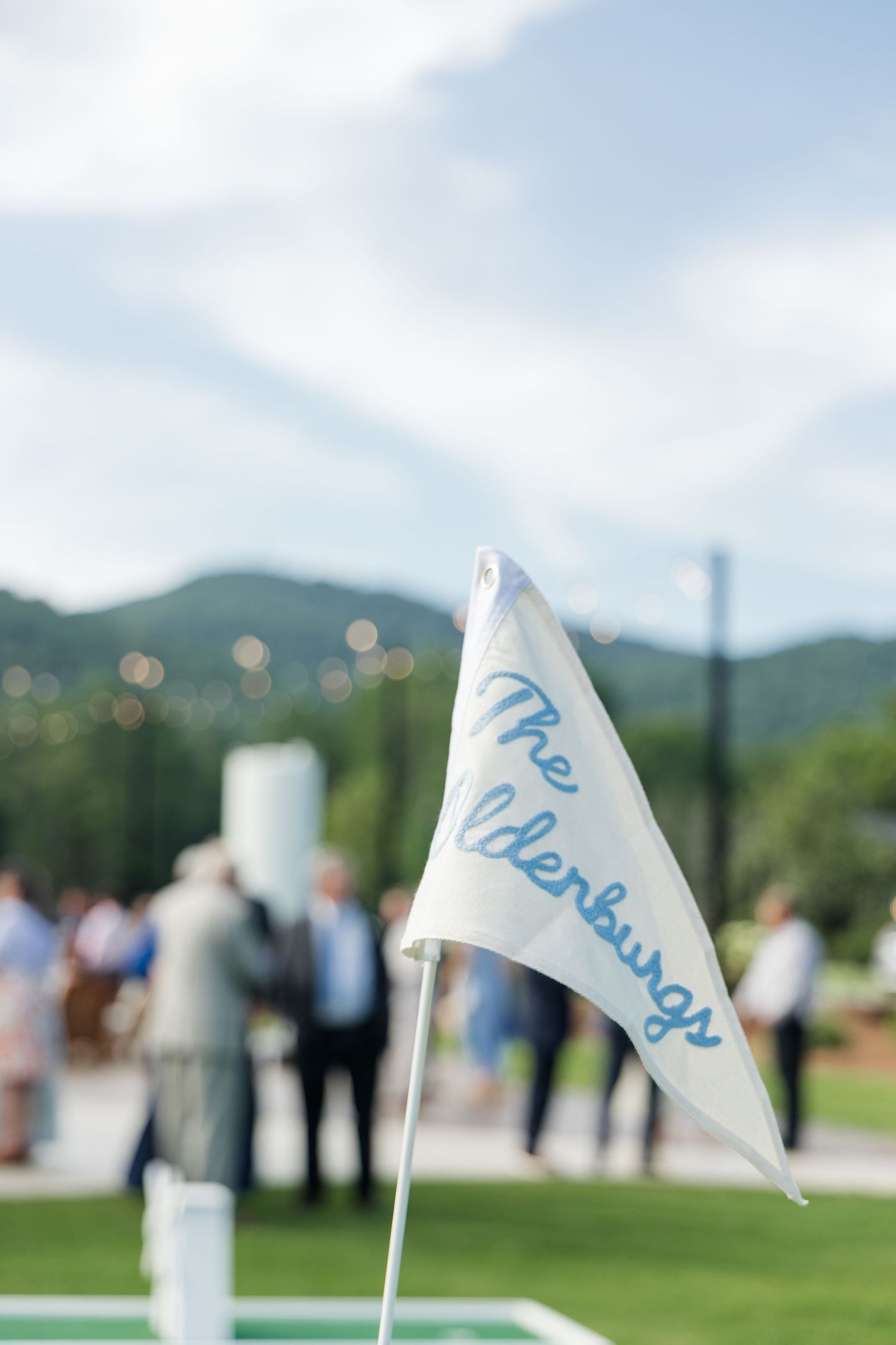 White pennant flag reading The Elderburgs at an outdoor wedding reception with mountain views.
