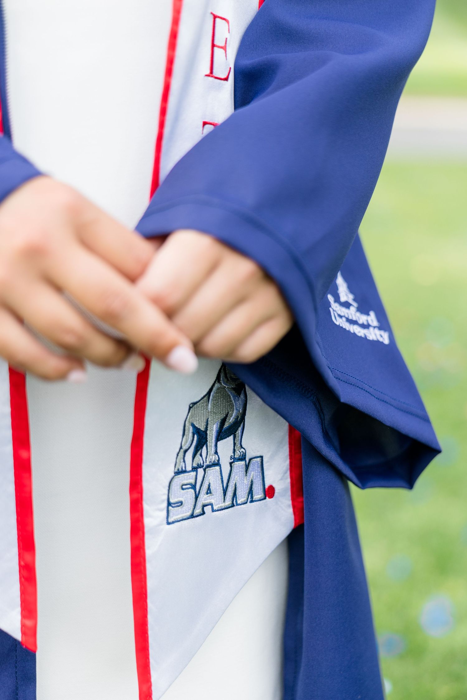 Close-up of Samford University graduation stole with SAM mascot logo on navy blue commencement gown.