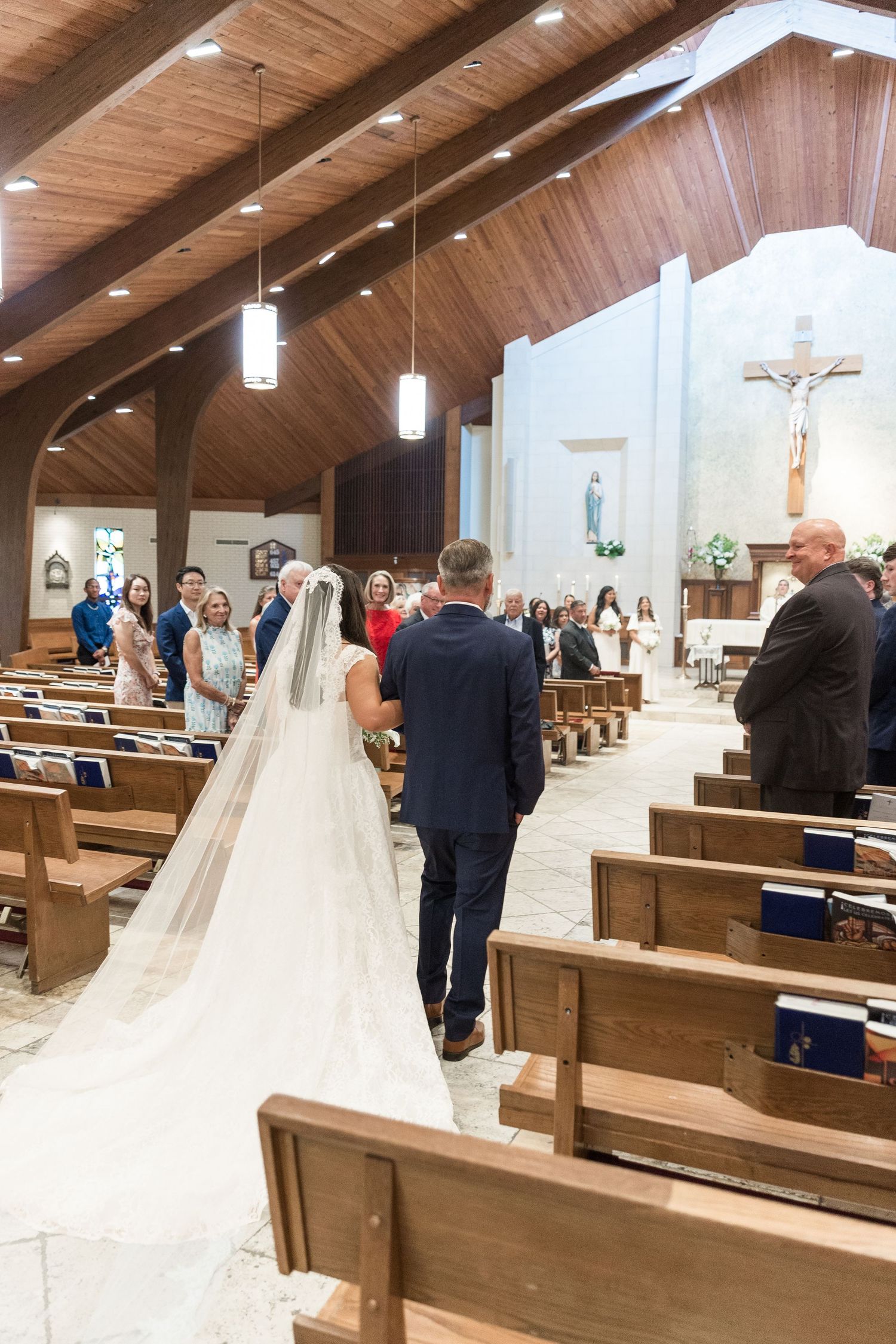 Bride walking down the aisle with escort in a Catholic church during wedding ceremony.