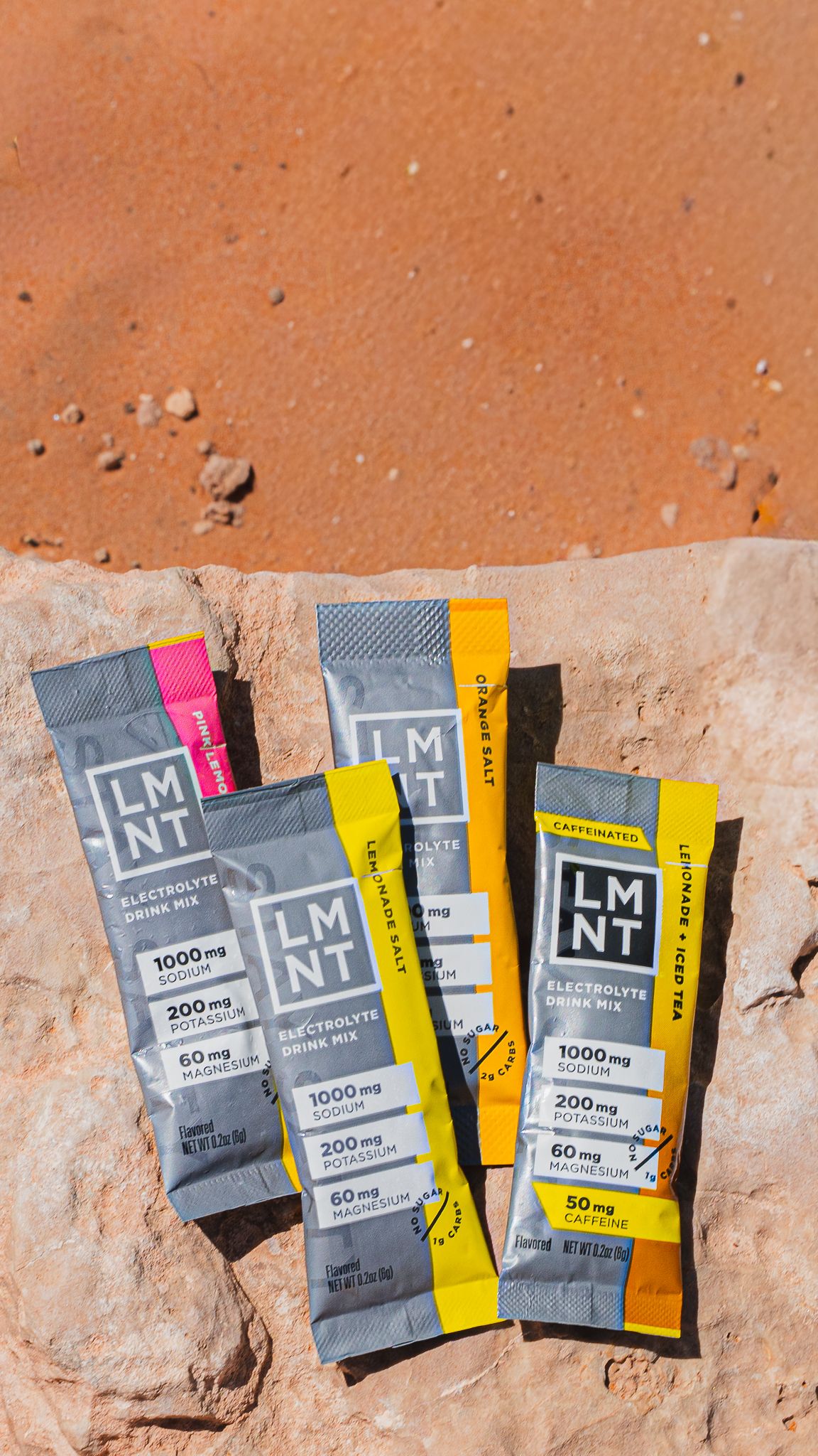 Multiple LMNT electrolyte drink mix packets displayed on red desert rock surface.
