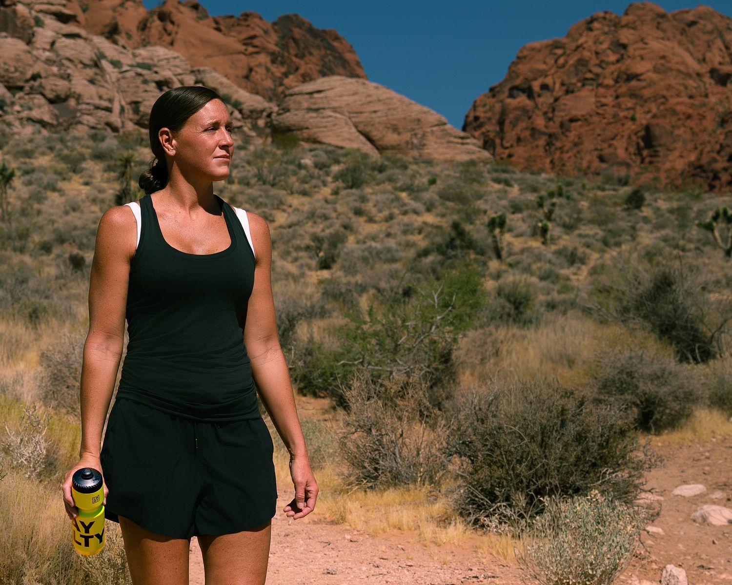 Woman hiking in black athletic wear through scenic red rock desert canyon trail.