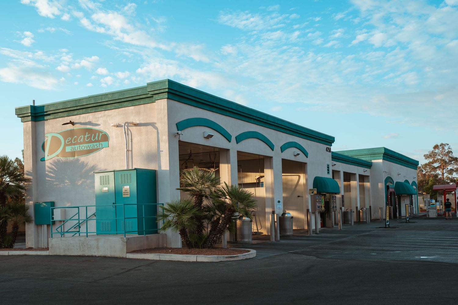 Exterior of Demetris restaurant with teal accents, arched windows, and palm trees in an empty parking lot at dusk.