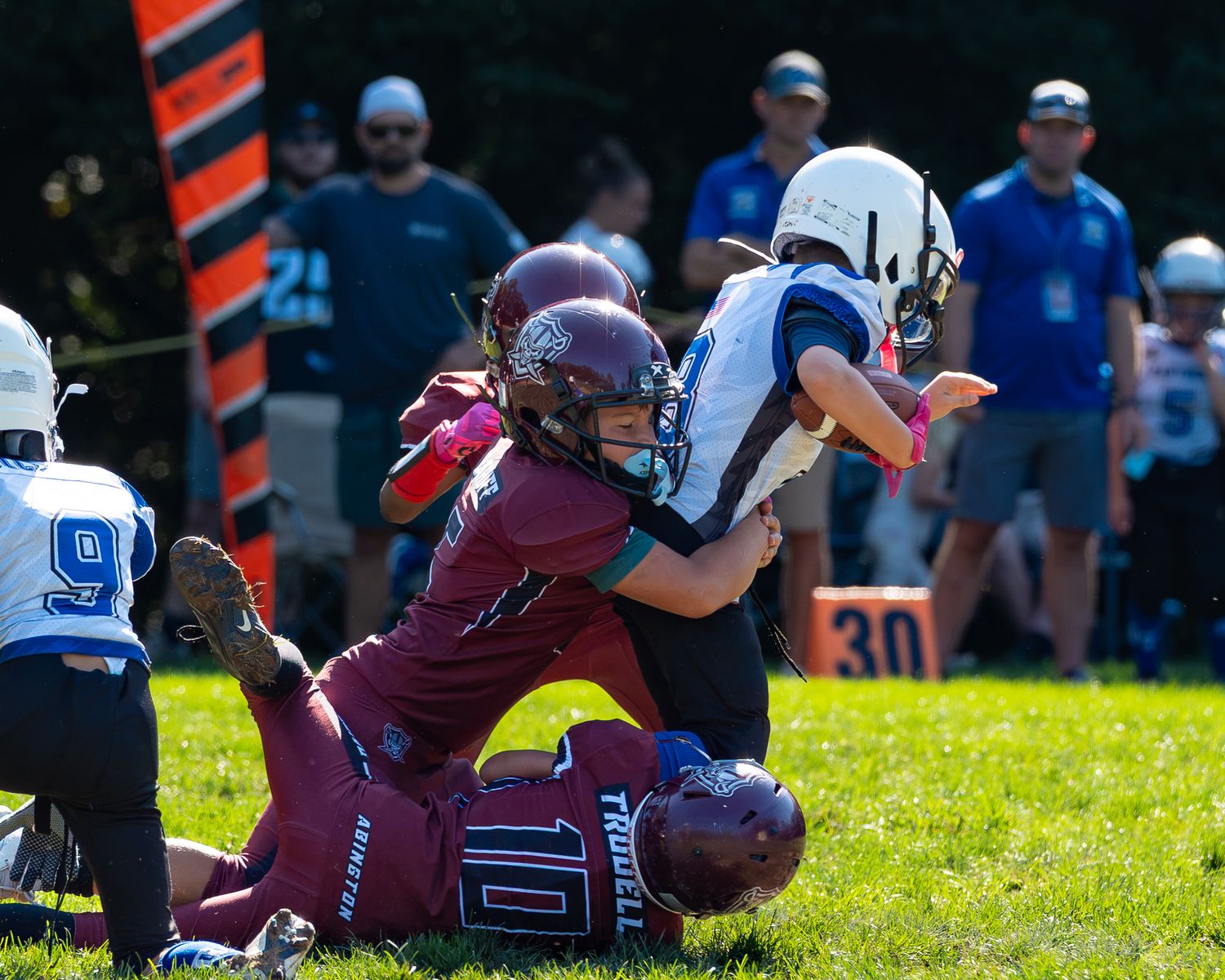 three abington raiders football players tackling the opposing team with the ball in hand