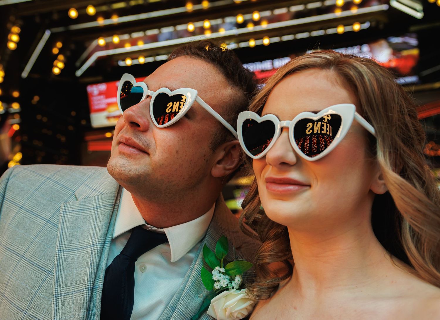 Couple wearing heart-shaped novelty sunglasses posing together at a casino wedding celebration.