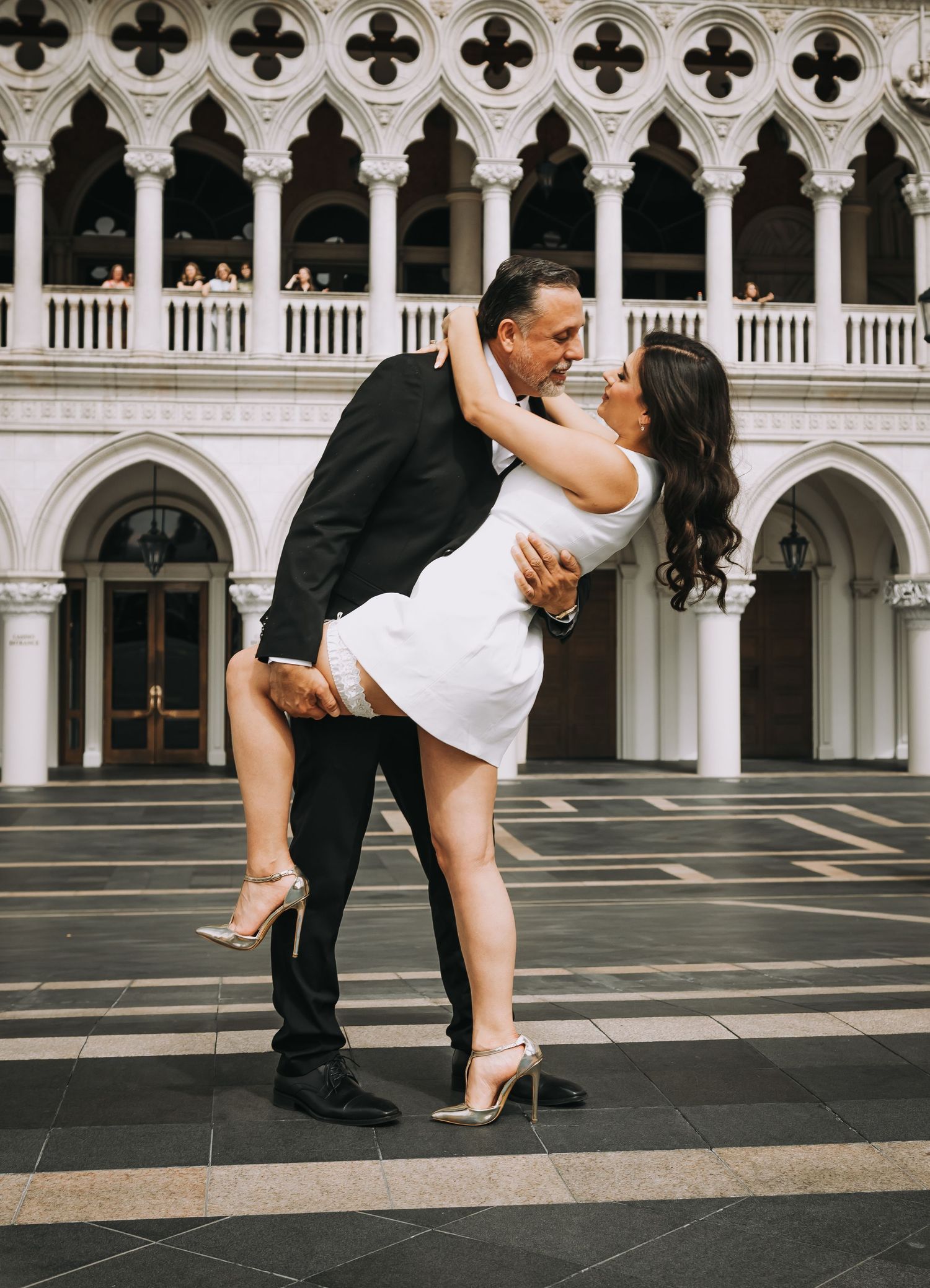 Couple sharing romantic dip kiss in front of ornate Venetian-style architecture at The Venetian Las Vegas.