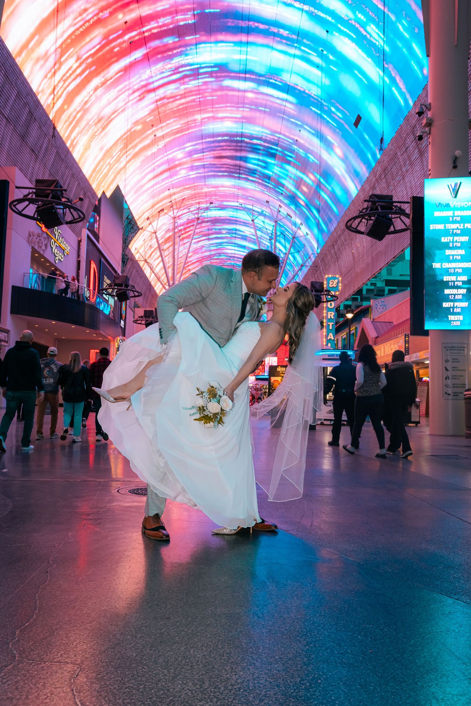Bride and groom sharing dip kiss under vibrant Fremont Street Experience LED canopy in Las Vegas.