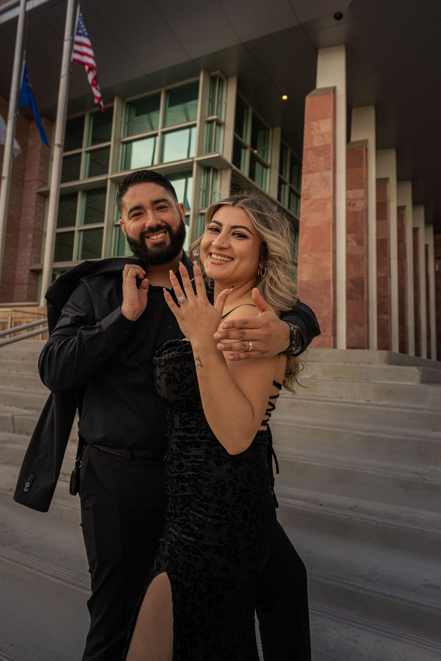 Smiling engaged couple proudly showing off their rings outside a Las Vegas courthouse.