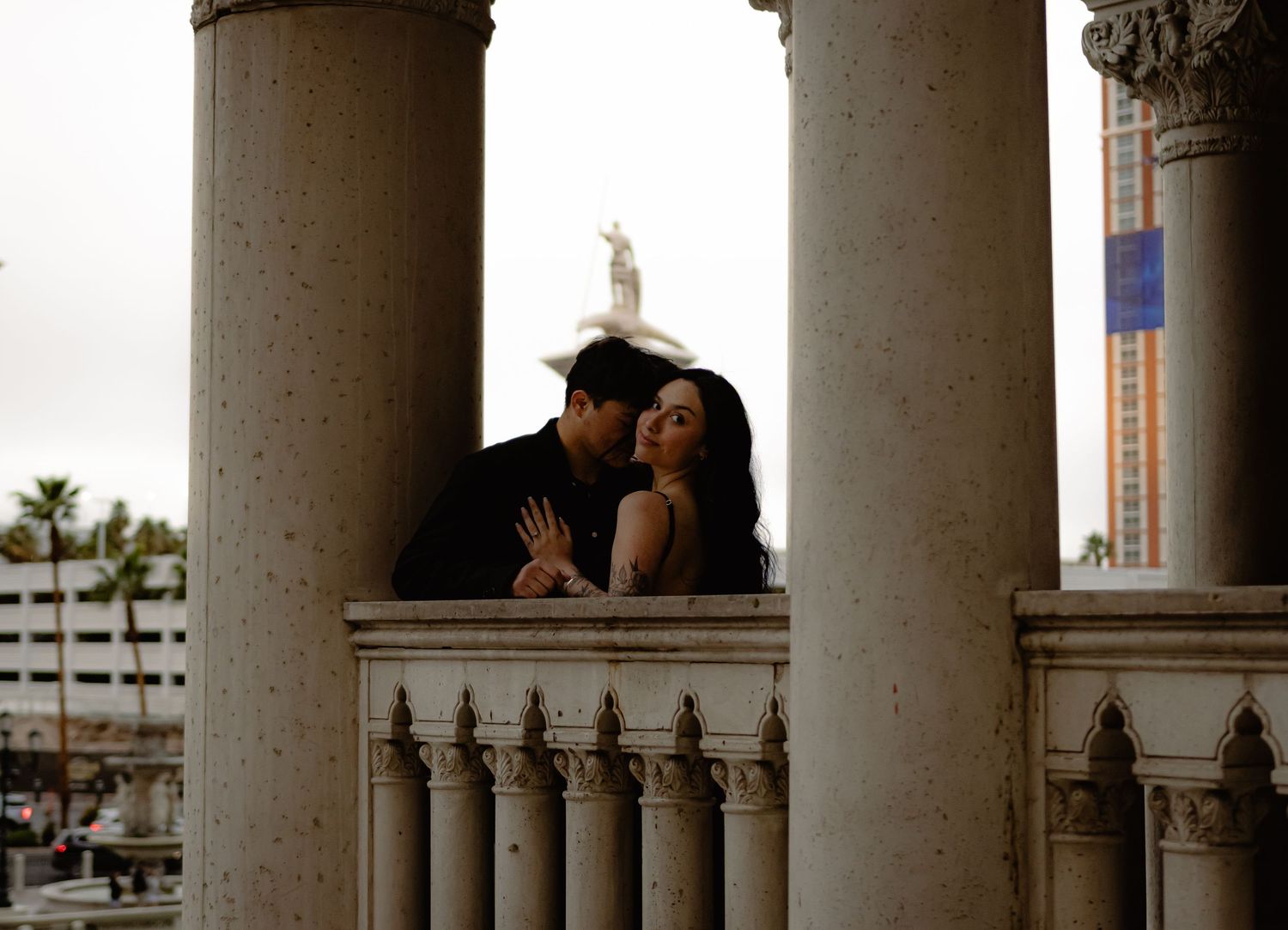 Couple posing romantically between grand columns on a balcony at The Venetian Las Vegas resort.